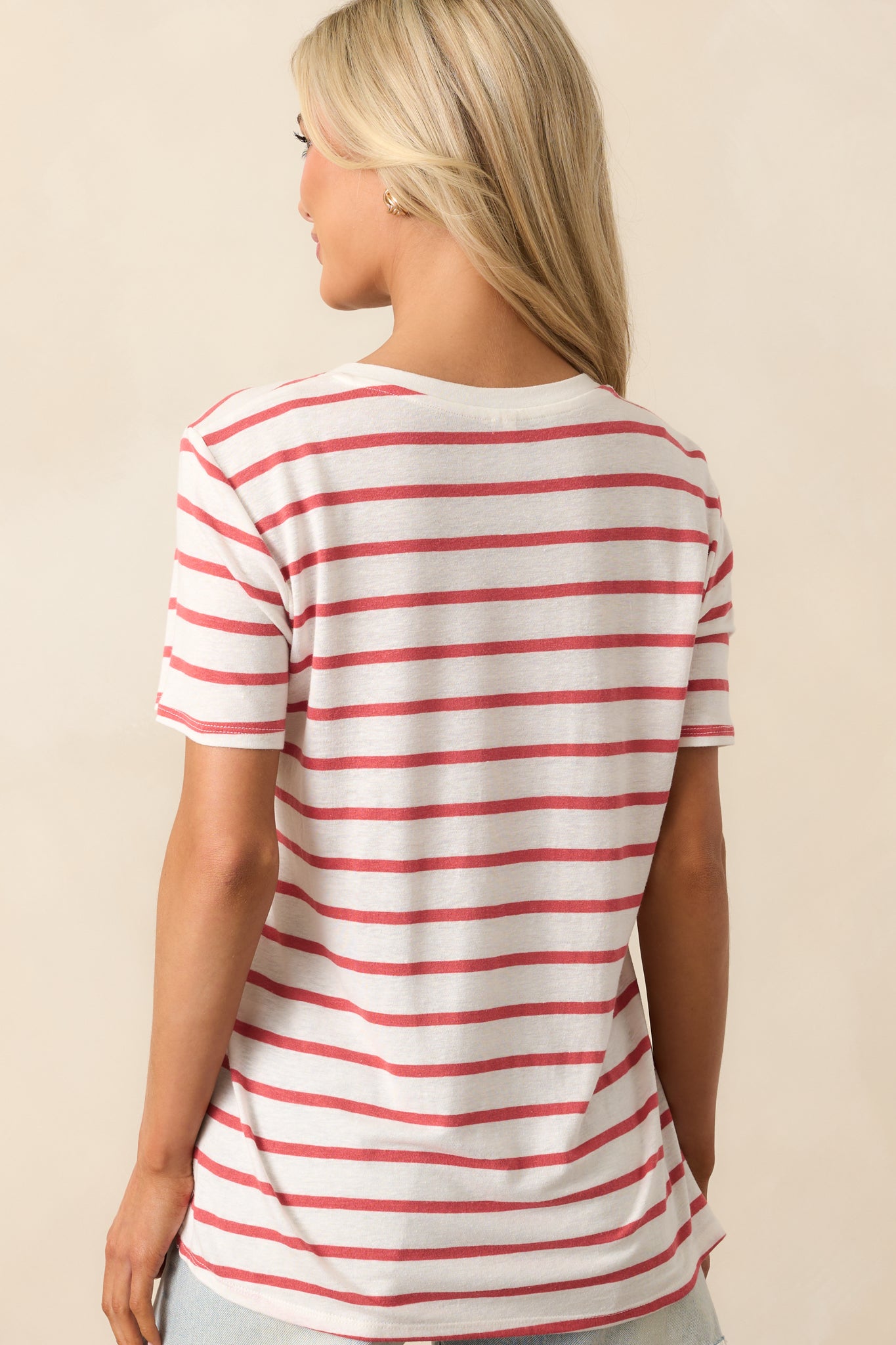 Back view of the light red and white striped top, emphasizing the relaxed fit and simple design with short sleeves and a clean, split bottom hem.