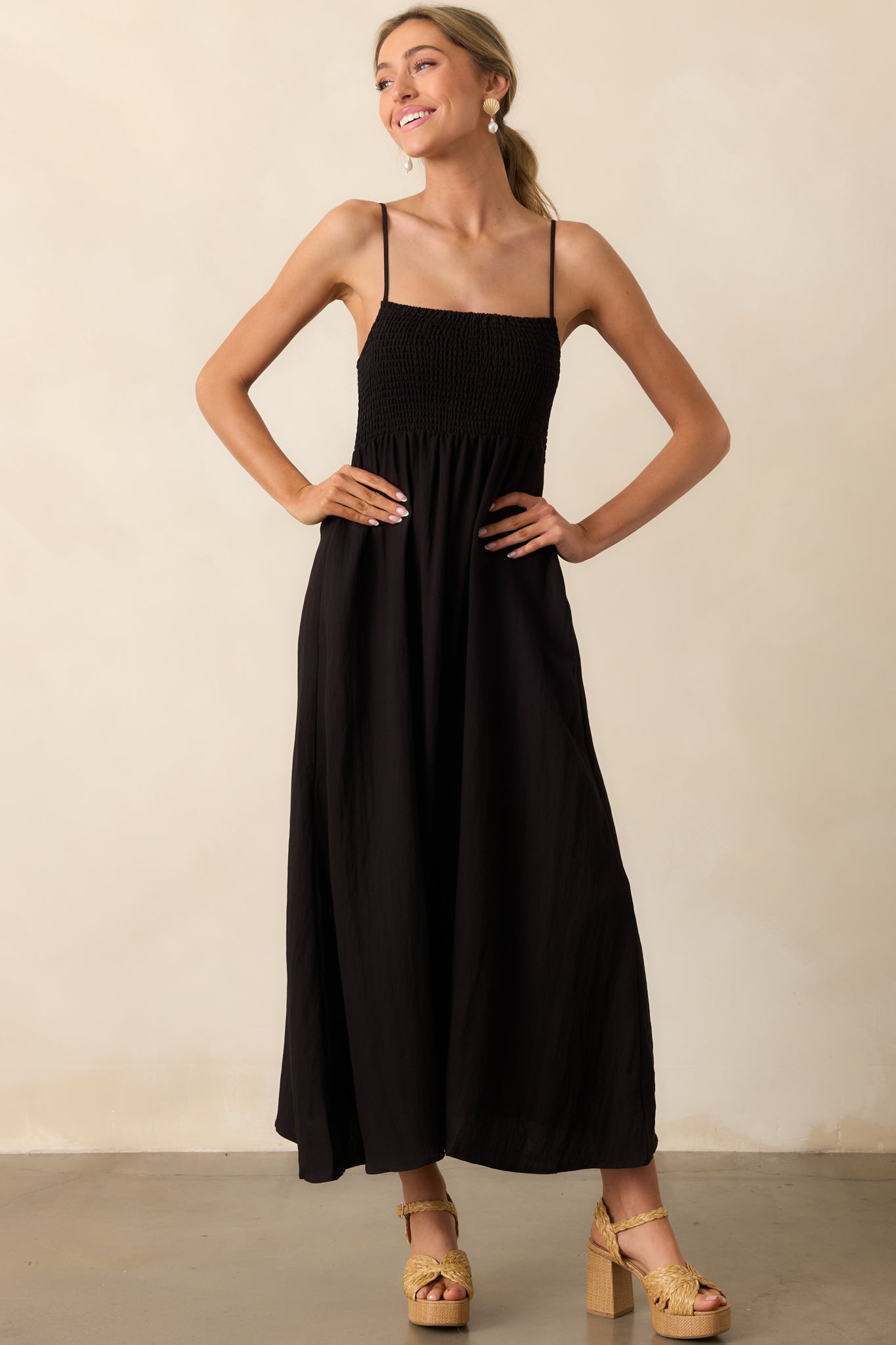 Black midaxi dress in a full view, highlighting the square neckline, adjustable straps, and functional side pockets.