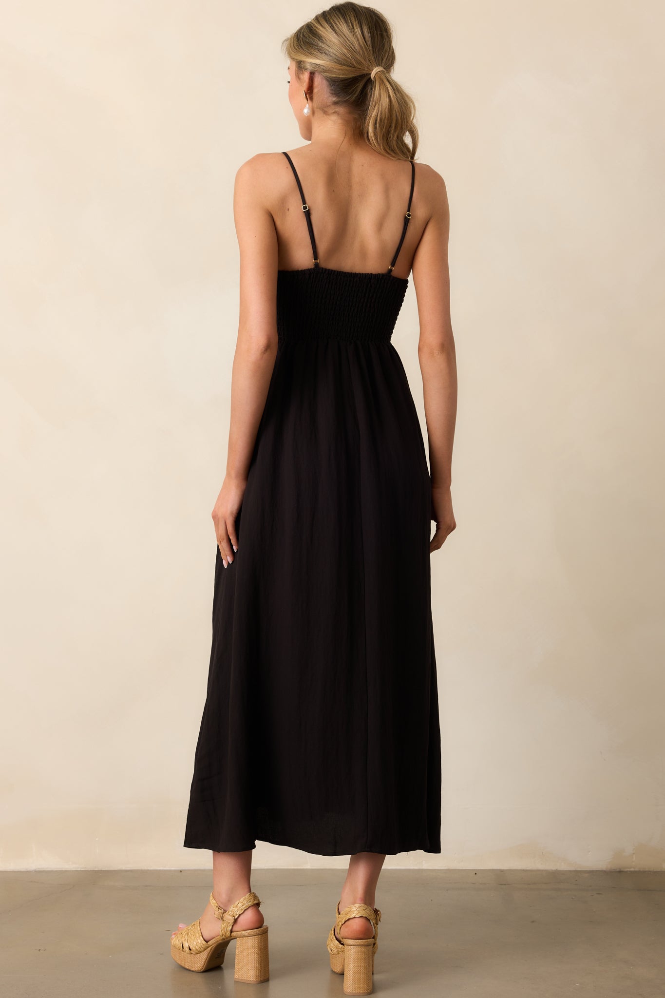 A view from behind showing the adjustable spaghetti straps and simple, elegant design of the black midaxi dress.