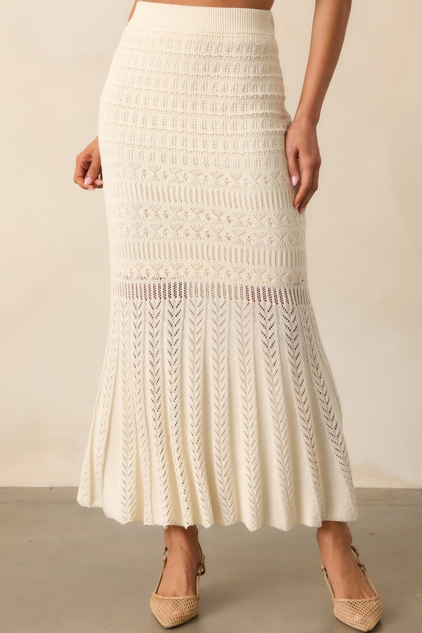 Detail of the elastic waistband and smooth fit of the crochet midi skirt, showing the mini-length beige lining beneath the open crochet overlay.