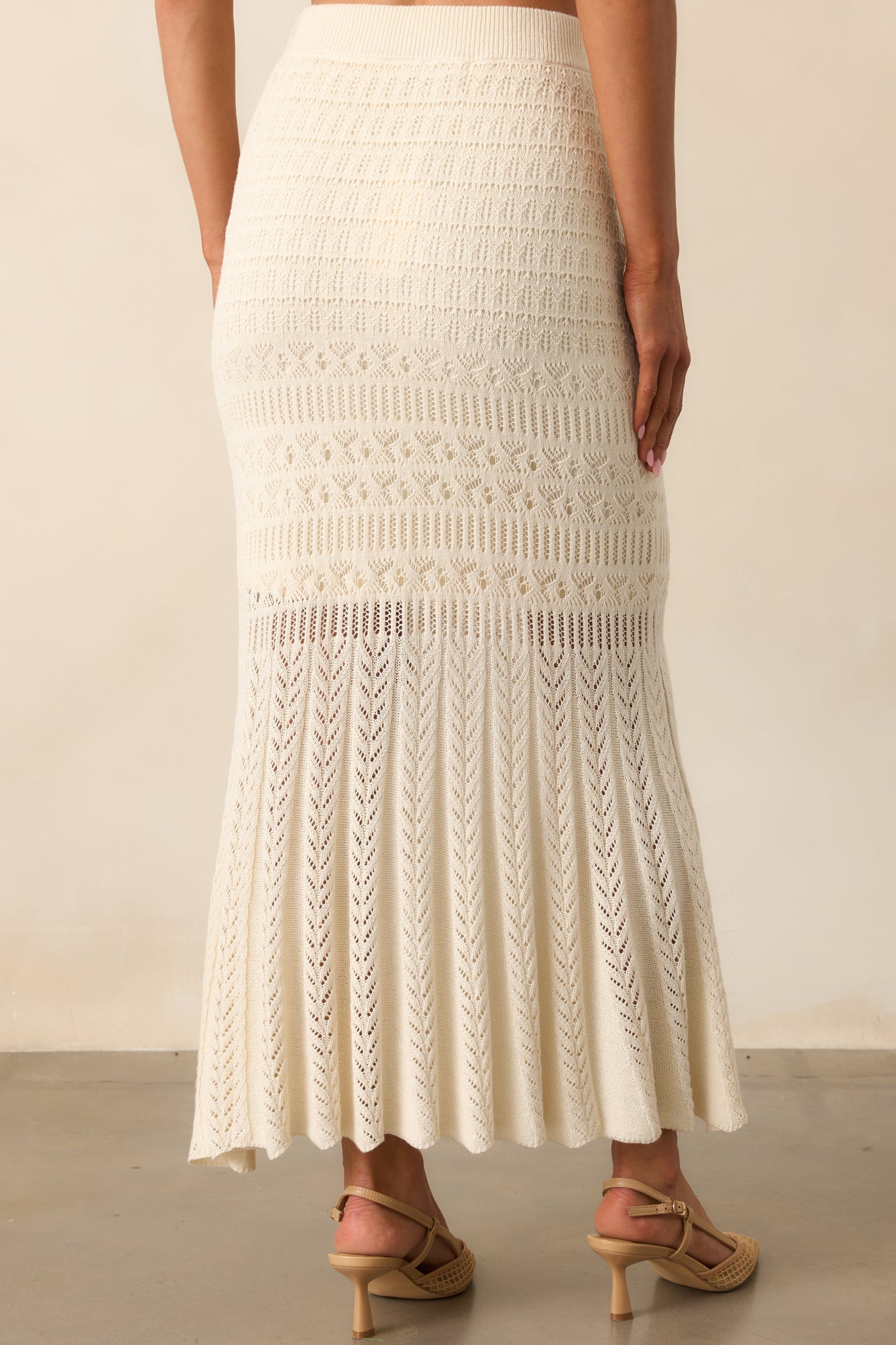 A view from behind of the crochet midi skirt showing the fitted silhouette, elastic waistband, and flare at the hem.