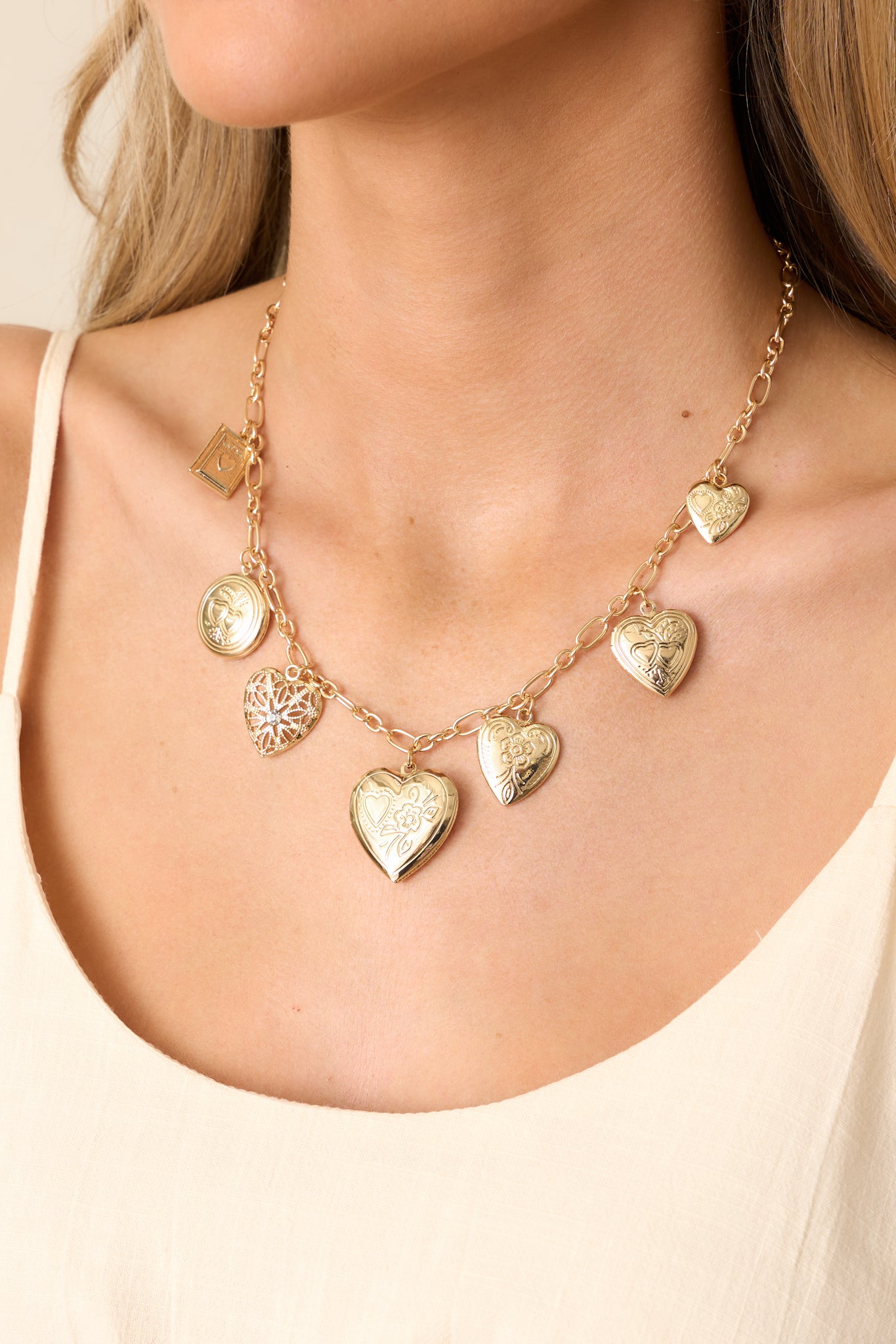 Cropped view of the gold heart charm necklace, showcasing the medium-sized rectangular chain and the assortment of heart charms.