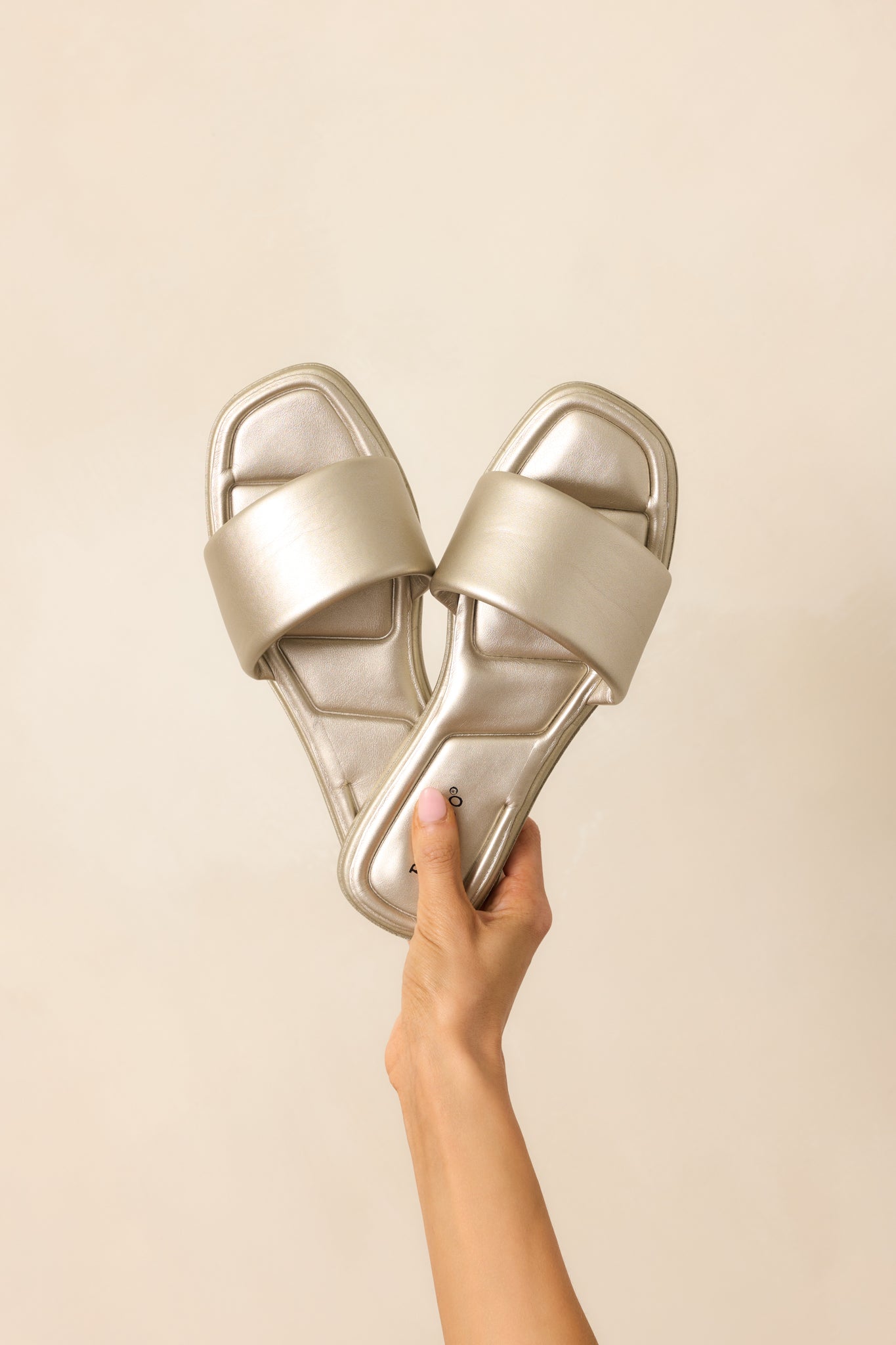 These gold sandals feature a square toe, a slip on design, a thick strap over the top of the foot, and cushioned soles.