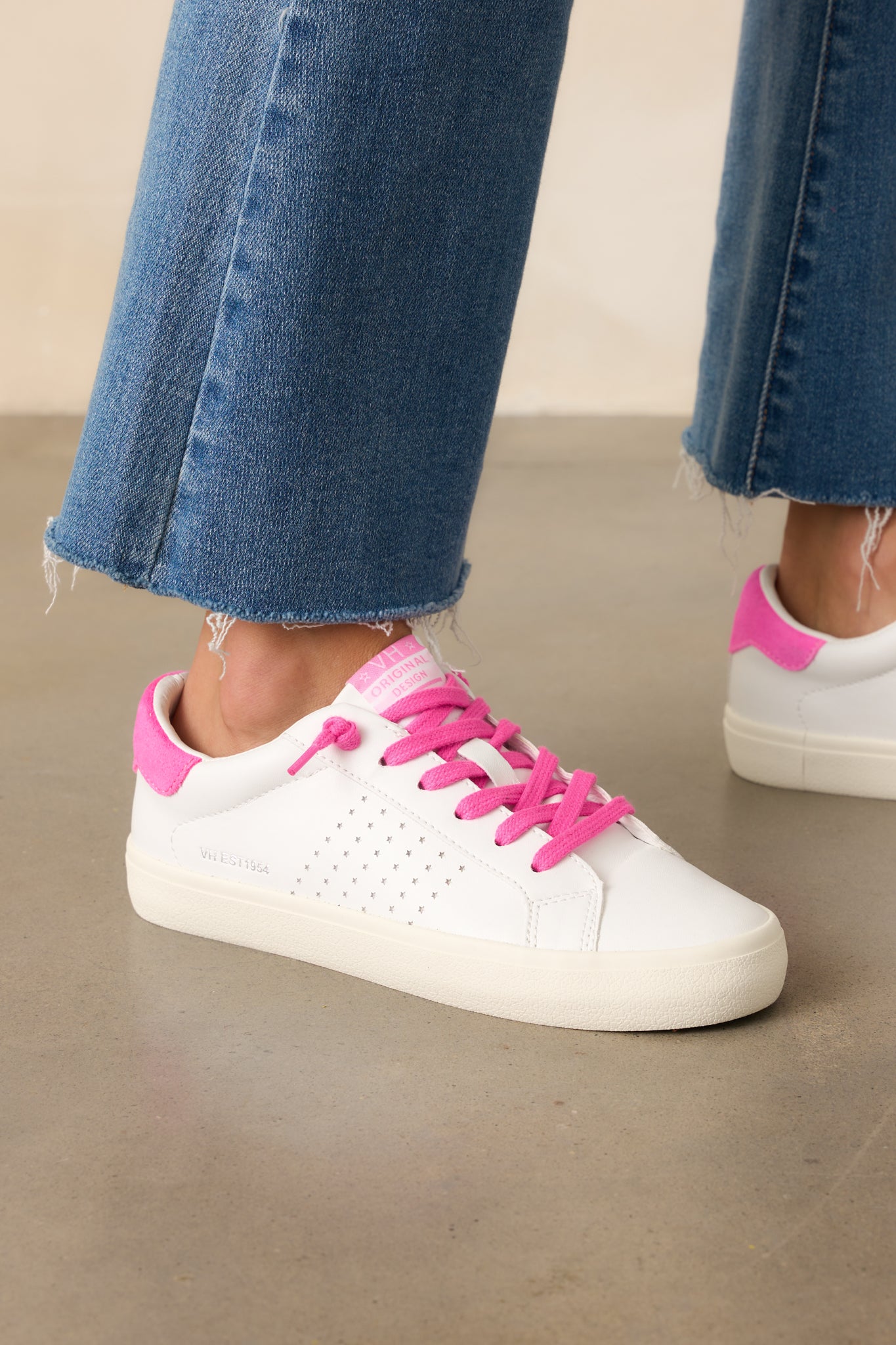 Side view of white faux leather sneakers highlighting the perforated panels and ivory textured rubber sole.