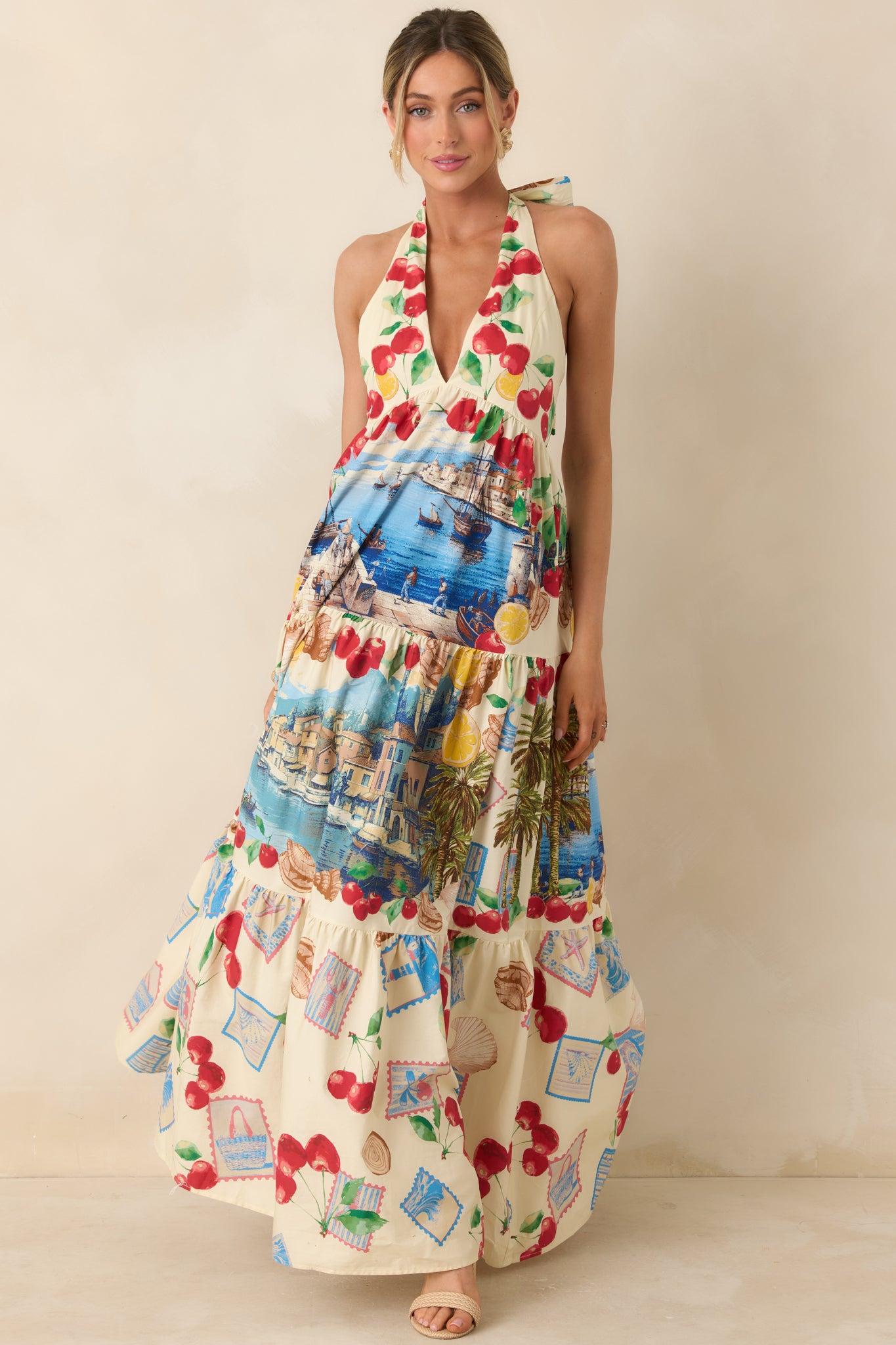 Lightweight halter dress with an open back silhouette and colorful prints showcasing cherries, lemons, and scenic coastal illustrations.
