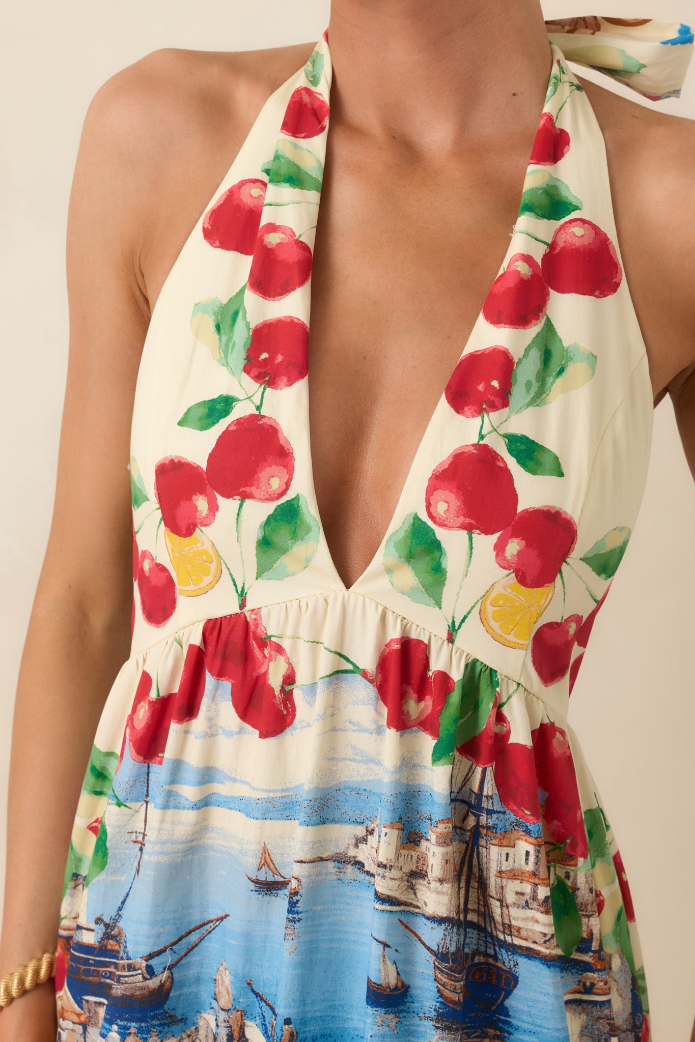 Detailed look at the Mediterranean-inspired print featuring lemons, cherries, and coastal motifs alongside the halter neckline and lightweight fabric texture.