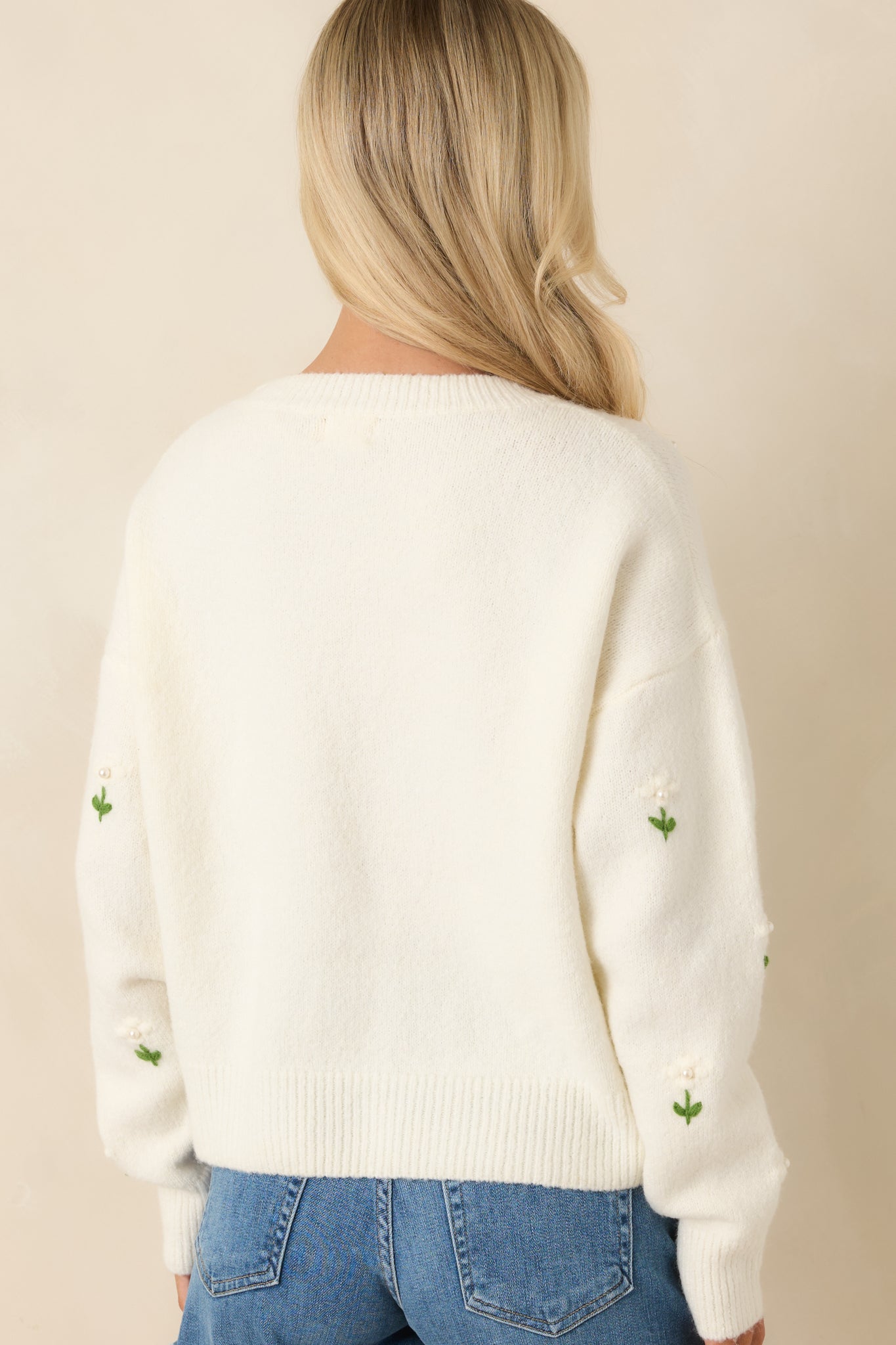 Back view of the ivory sweater highlighting the clean knit finish and ribbed hem without embellishments.
