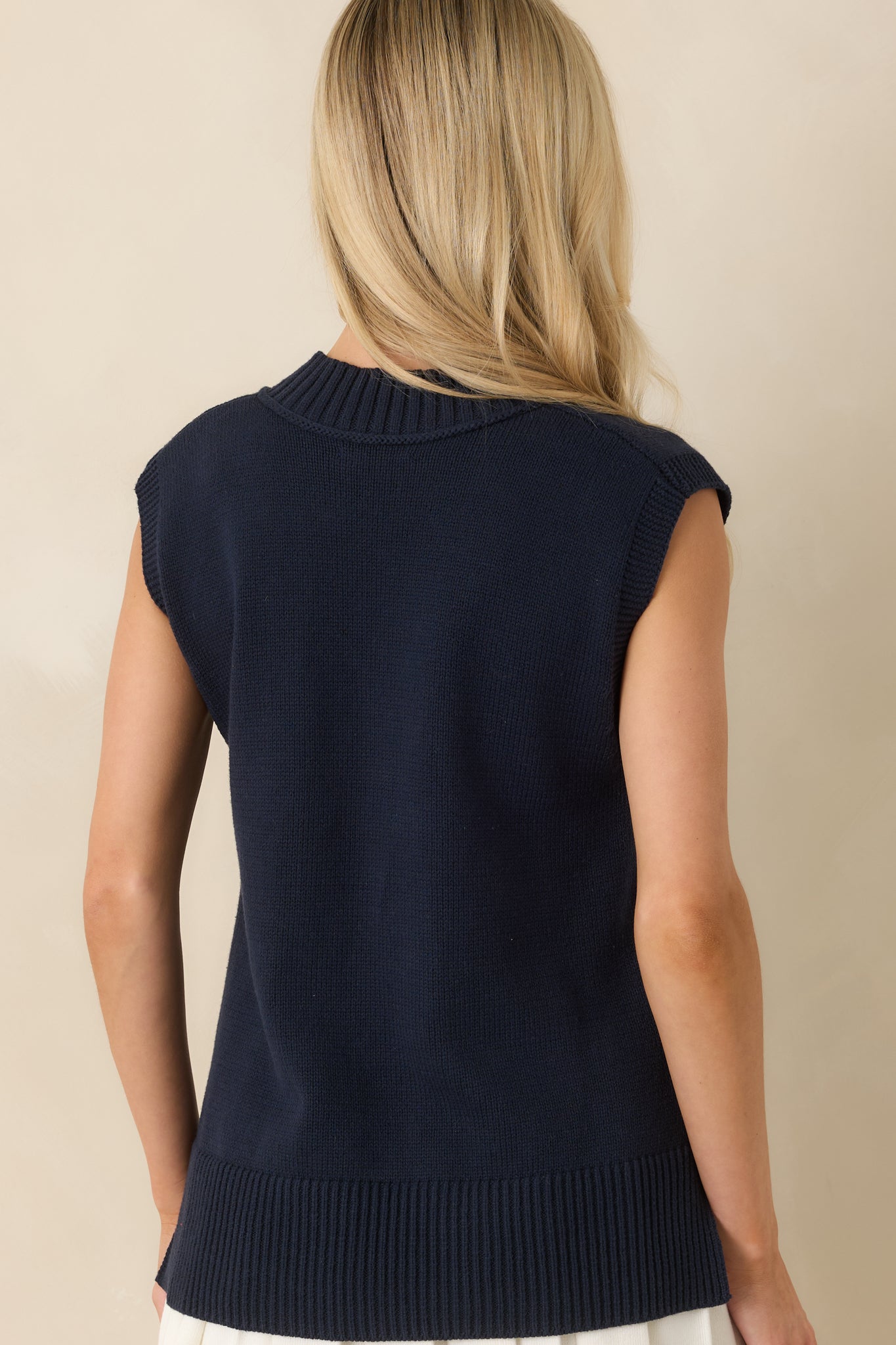 Back view of the navy knit sweater vest featuring a smooth sleeveless cut, relaxed fit, and wide ribbed hemline.