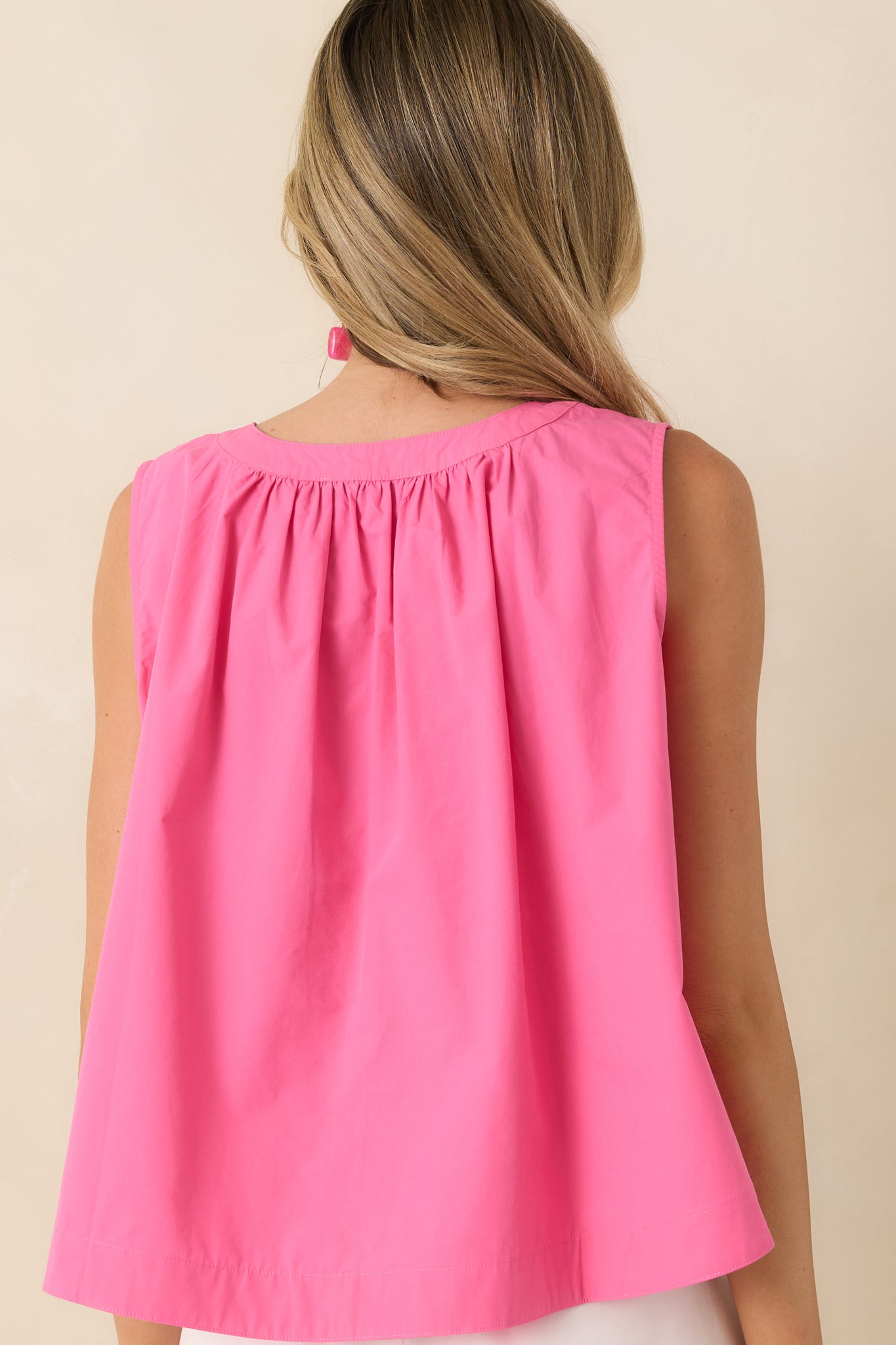 Rear view of the pink cotton blouse highlighting the sleeveless silhouette and relaxed drape through the back.