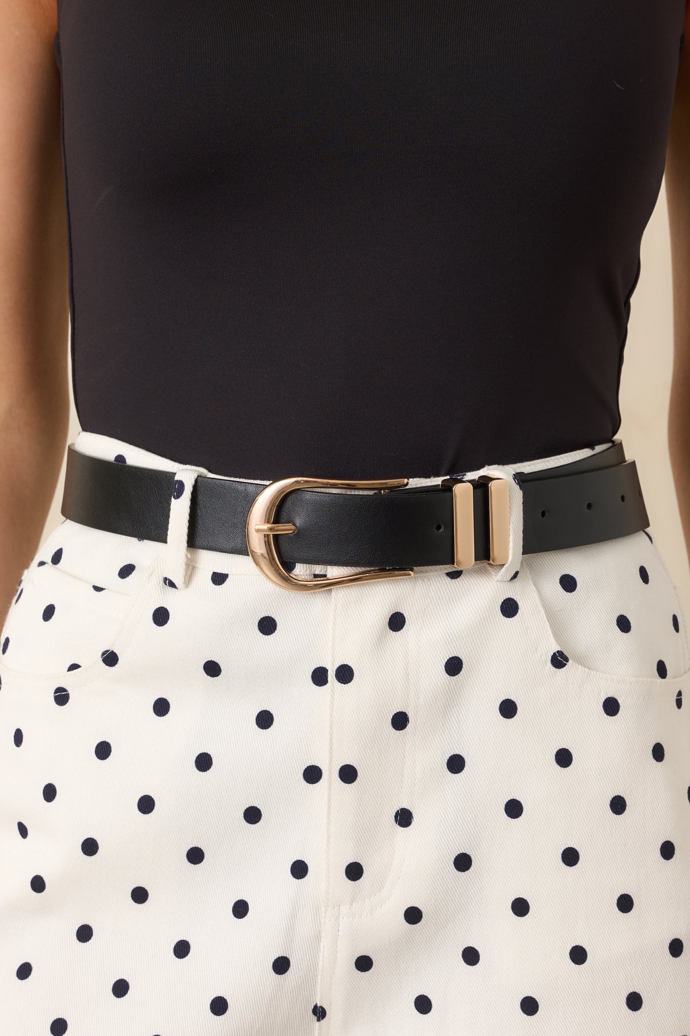 Close-up detail of belt showing horseshoe buckle, gold hardware, and precise stitching.