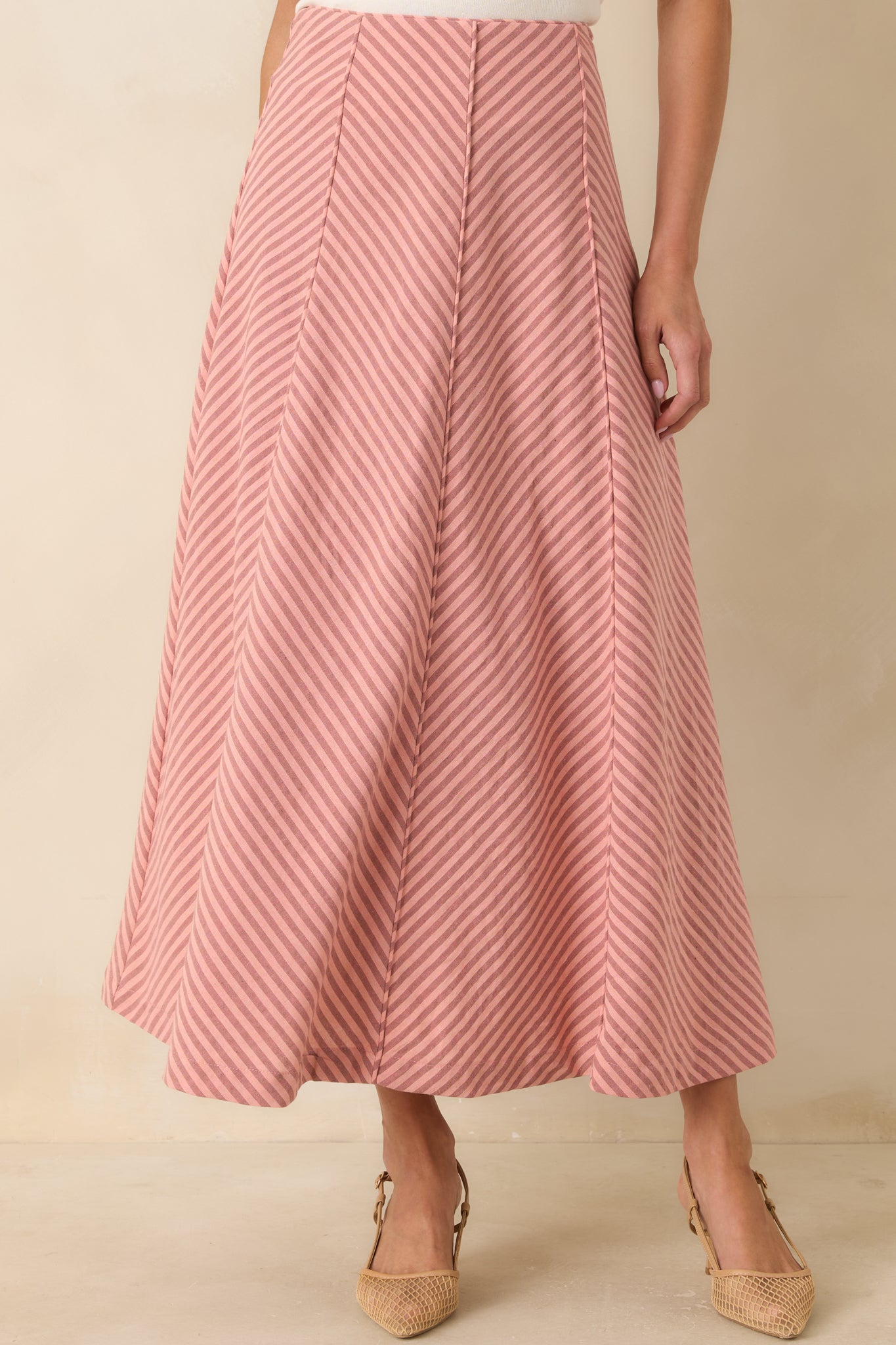 Detailed crop focusing on the softly flared silhouette and fluid movement of the coral stripe skirt.