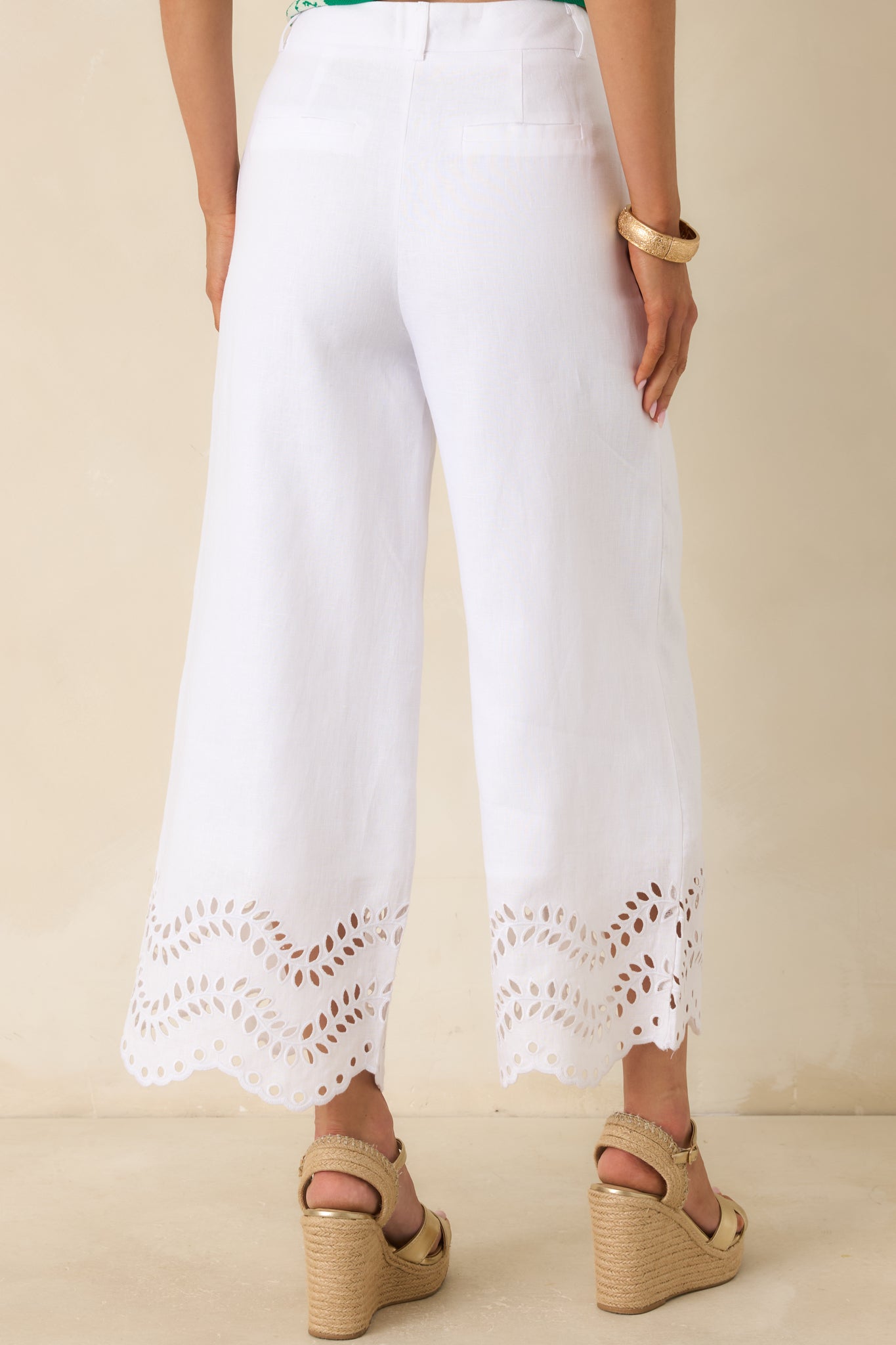 Rear view of the white wide leg pants featuring faux welt back pockets and a smooth, tailored finish.