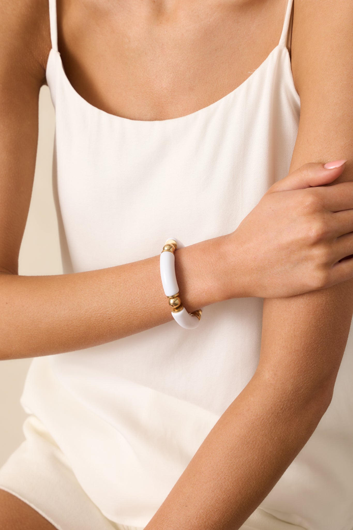 Close-up cropped image showing a section of the bracelet’s solid white beads alternating with thin gold flat circle beads.