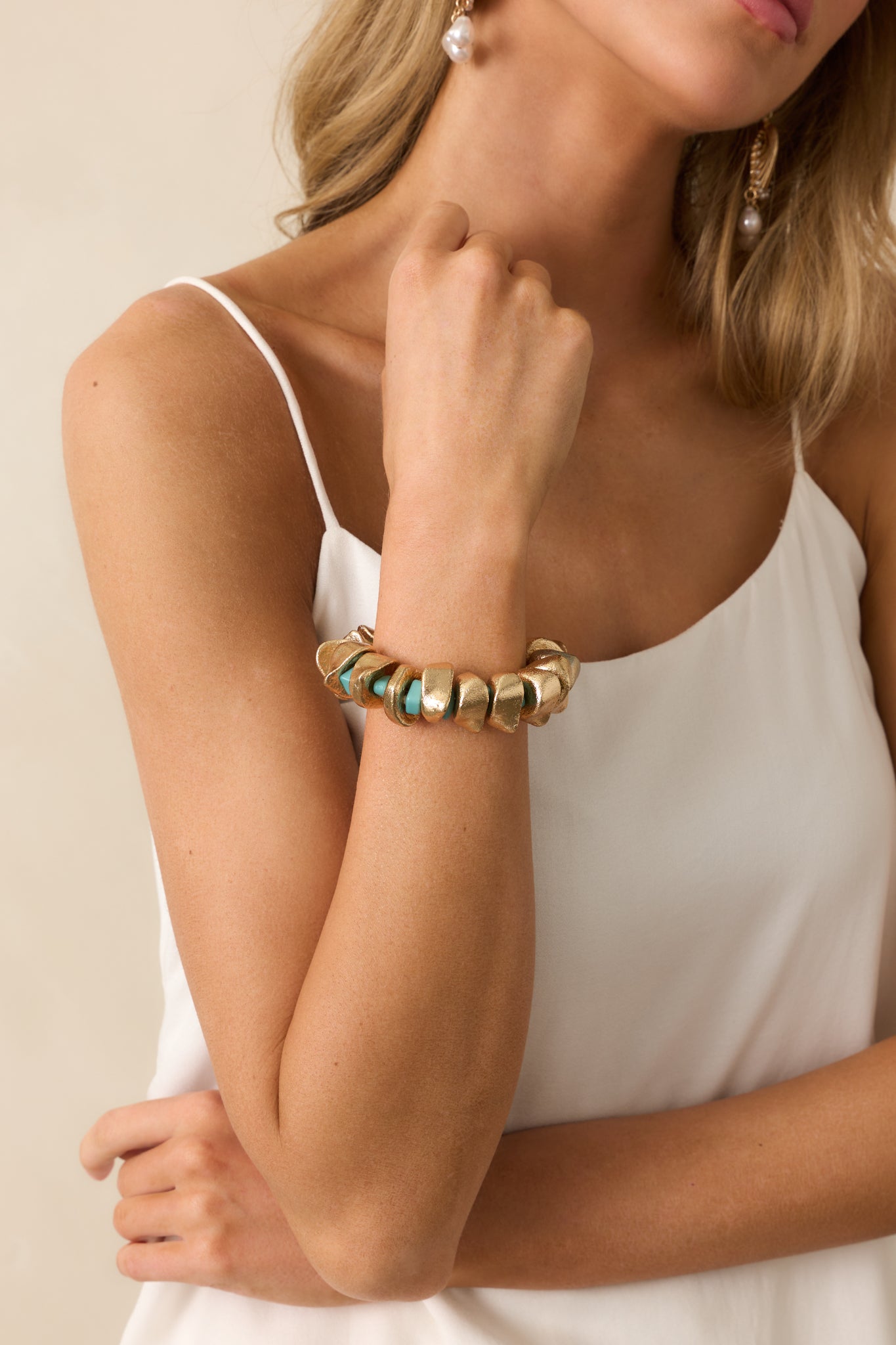 Cropped image of the bracelet’s elastic band, highlighting the texture and pattern of the gold and turquoise beads.