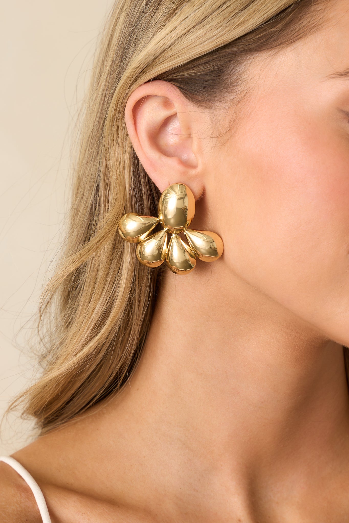 Close-up cropped view of the earrings showing the chunky gold oval base with attached teardrop-shaped segments.