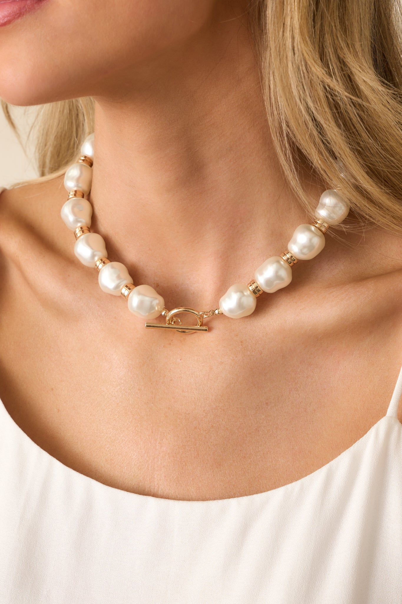 Zoomed-in angle highlighting the toggle closure and part of the pearl-gold bead design of the necklace.