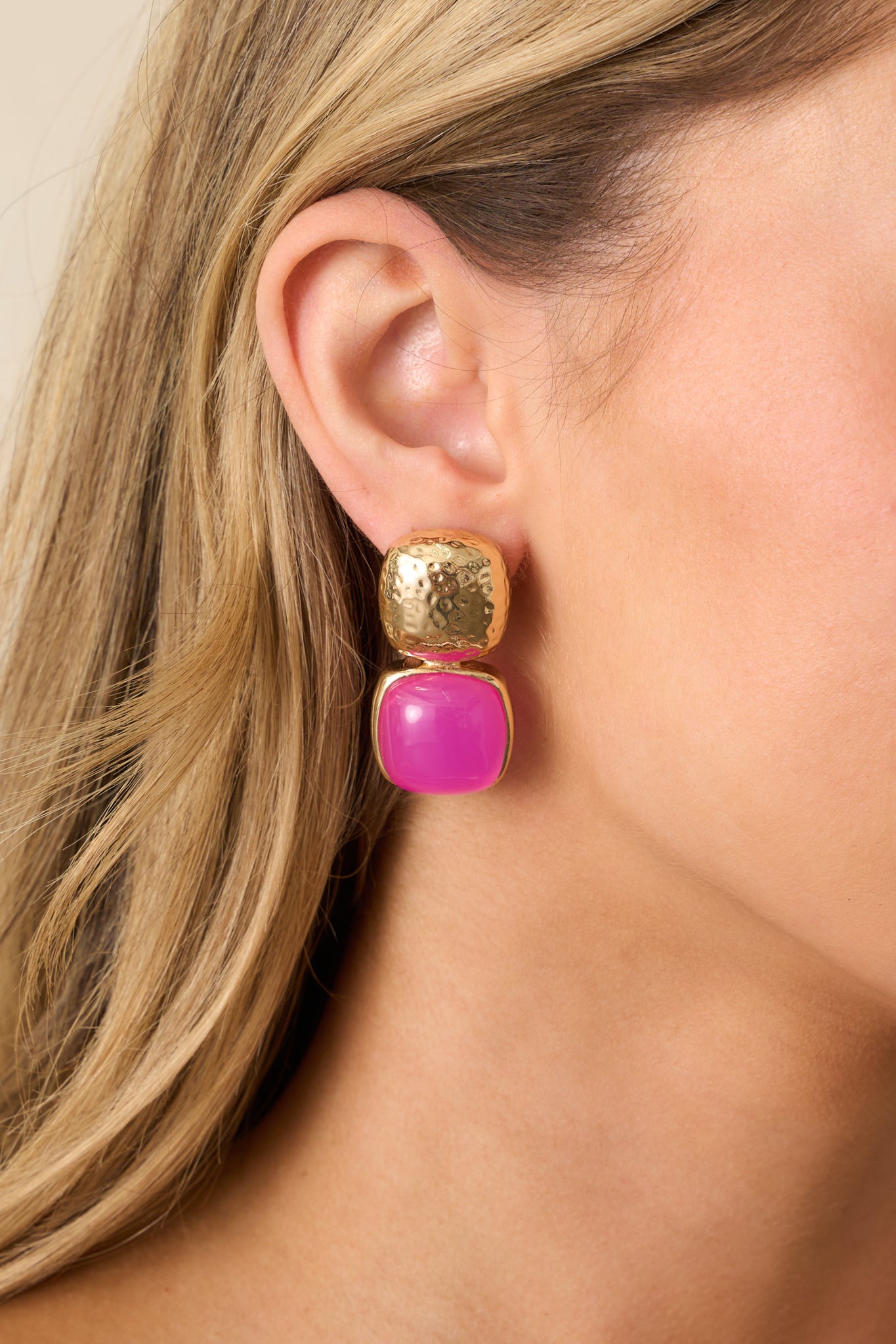 Close-up of gold textured square stud earrings with pink faux pearl square drops, highlighting their geometric design.