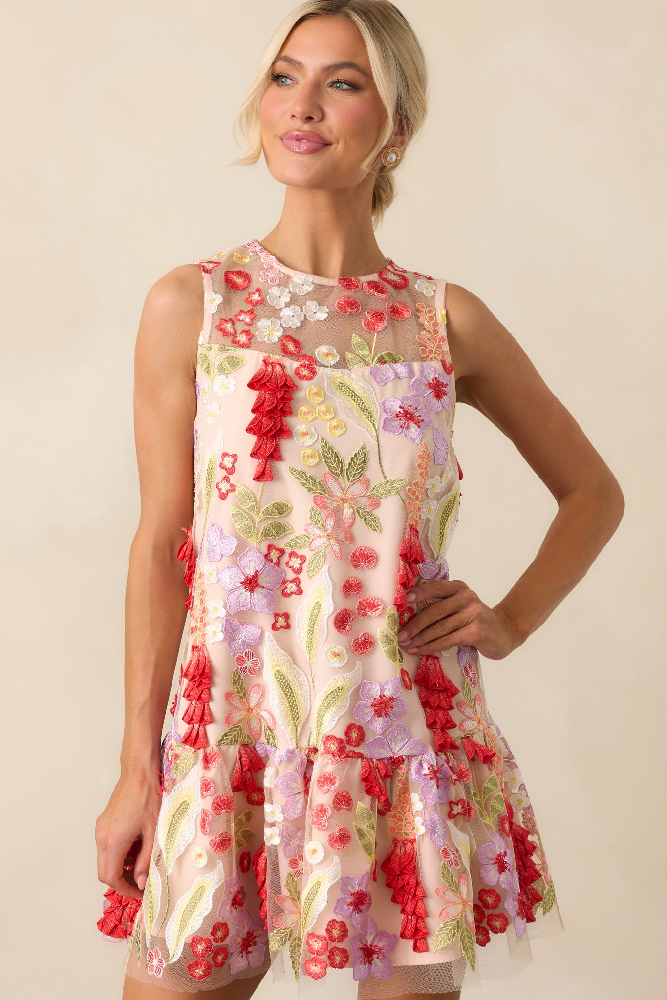 Close-up of the high round neckline and sleeveless cut on the mini dress with 3D embroidered floral details.