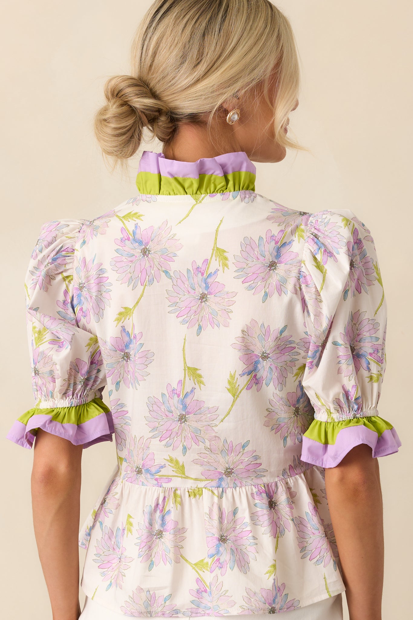 Rear view of the top showcasing the continued floral print, peplum silhouette, and puff sleeve shape from behind.