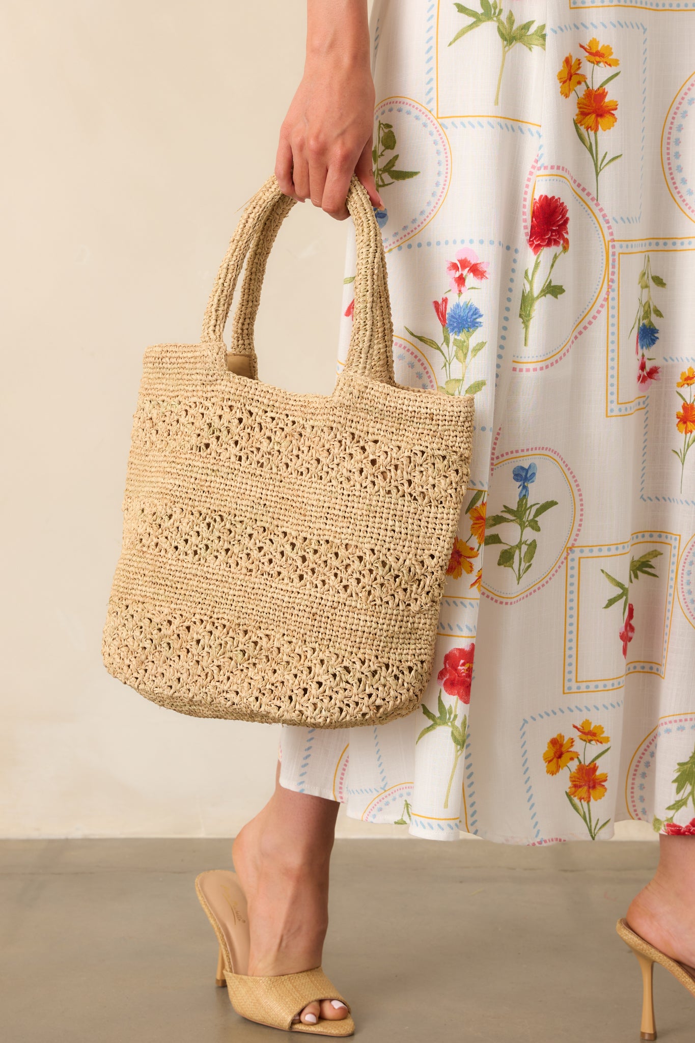 A cropped view showing the texture and detailed alternating weave designs of the natural raffia straw handbag.