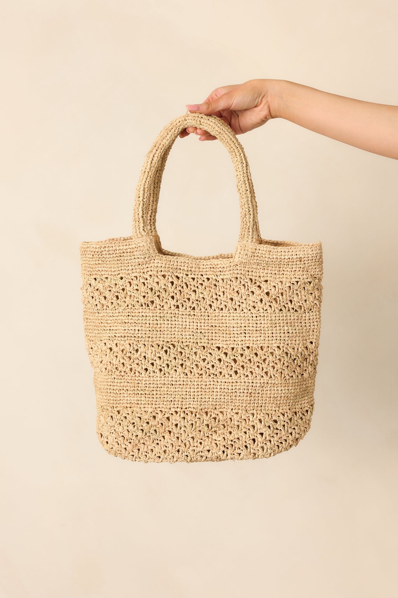 A front view of the natural woven raffia straw handbag featuring alternating weave patterns and a structured shape.