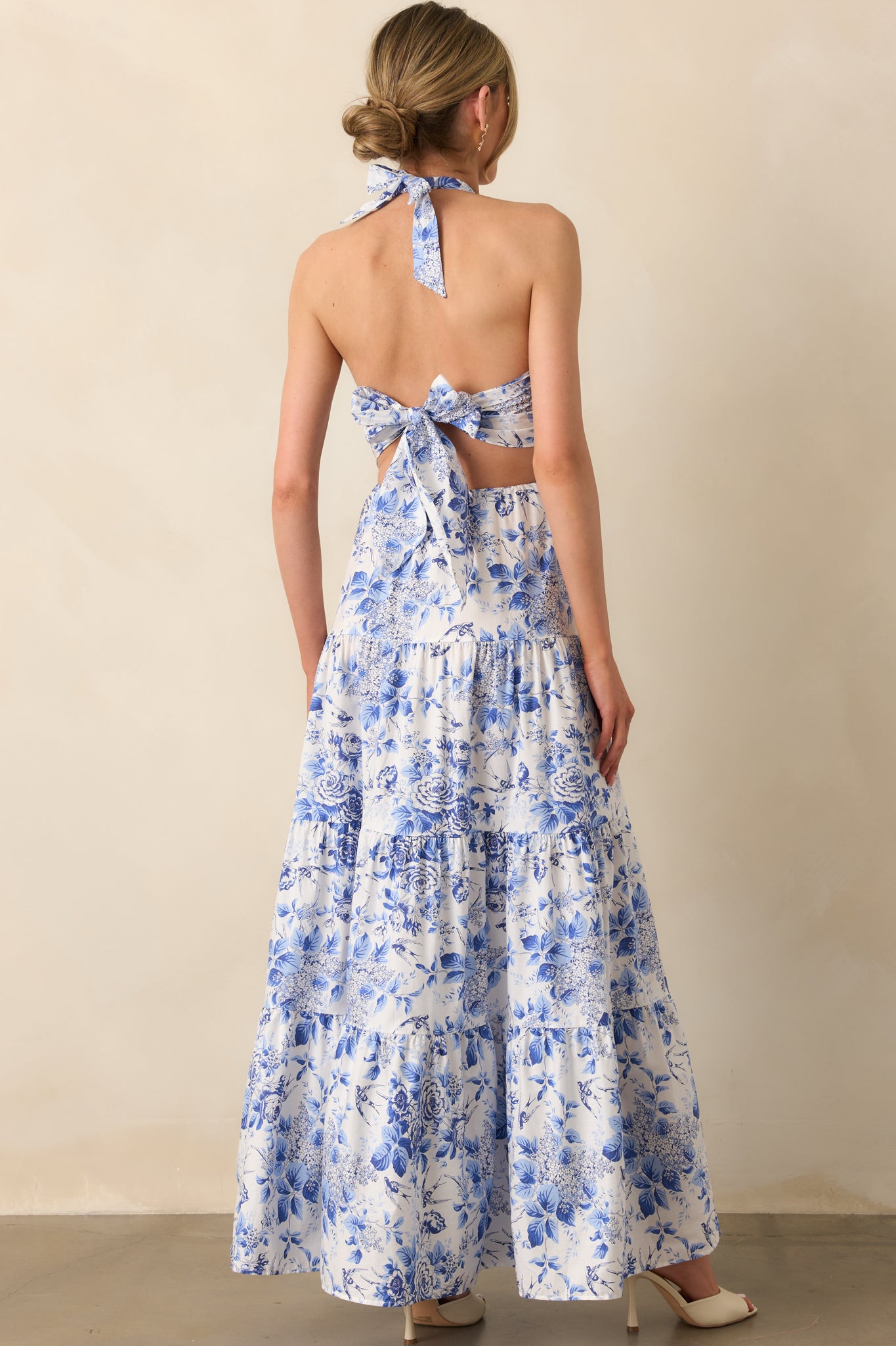 Rear view of the maxi dress revealing the open back design, self-tie bow at the waist, and subtle gathering at the elastic waistband.