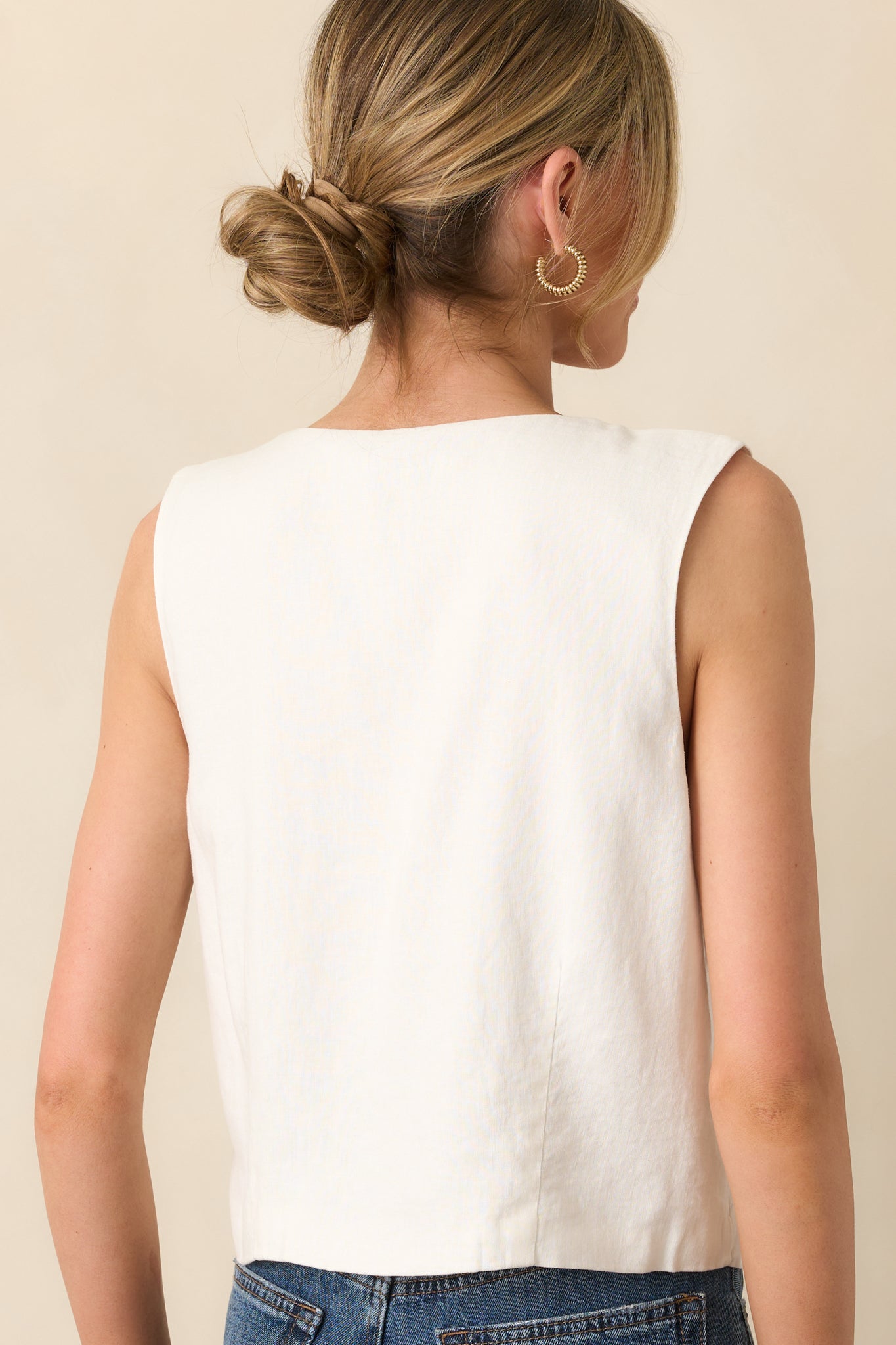 A view from behind of the white vest, showing the sleeveless cut and slightly cropped hemline in lightweight linen.