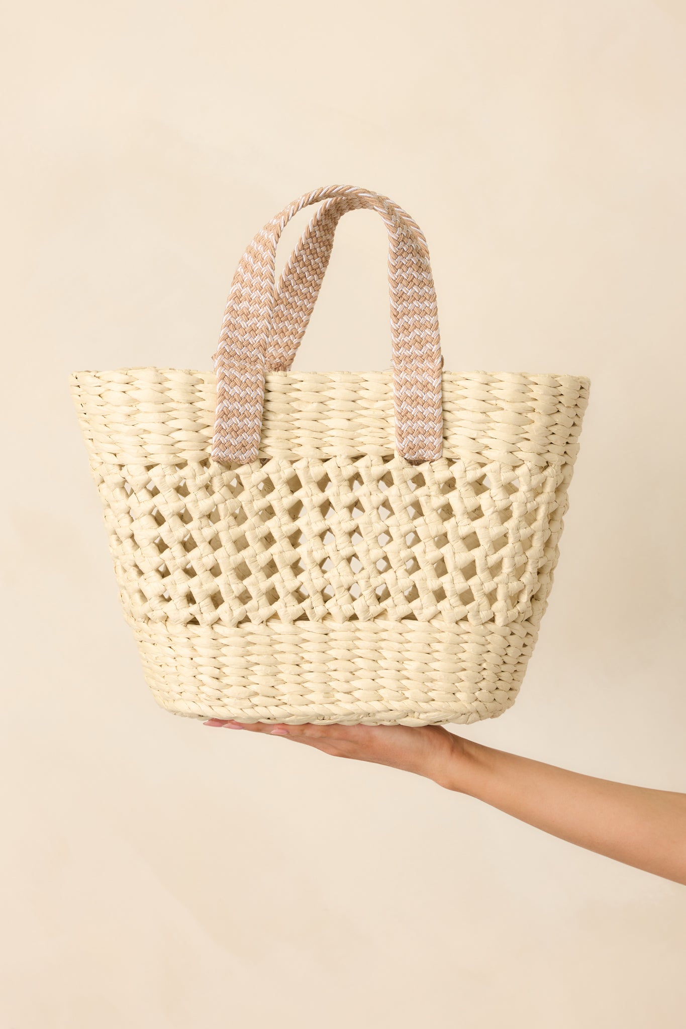 Closer view of the top half of the bag, highlighting the tan woven handles and detailed raffia texture.