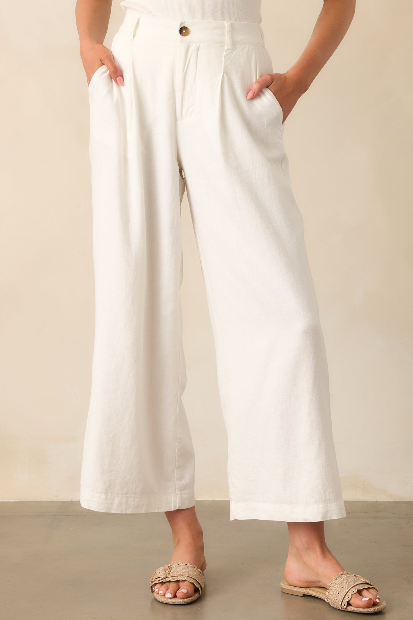 Cropped view of the upper portion of the pants, focusing on the tortoise shell button closure and pleated front.