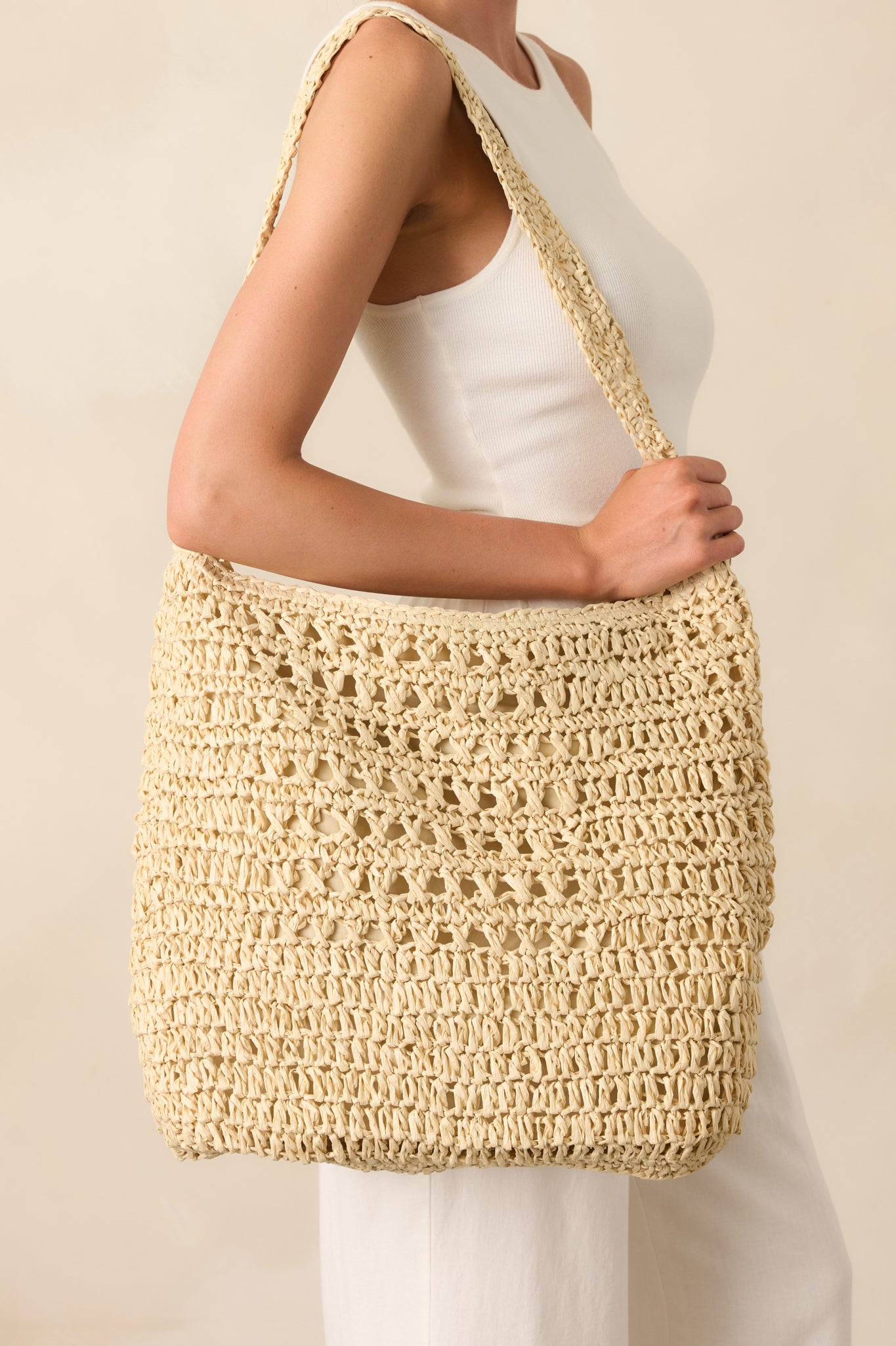 A front crop of the bag emphasizing the ivory raffia weave and the seamless curve of the wide shoulder strap.