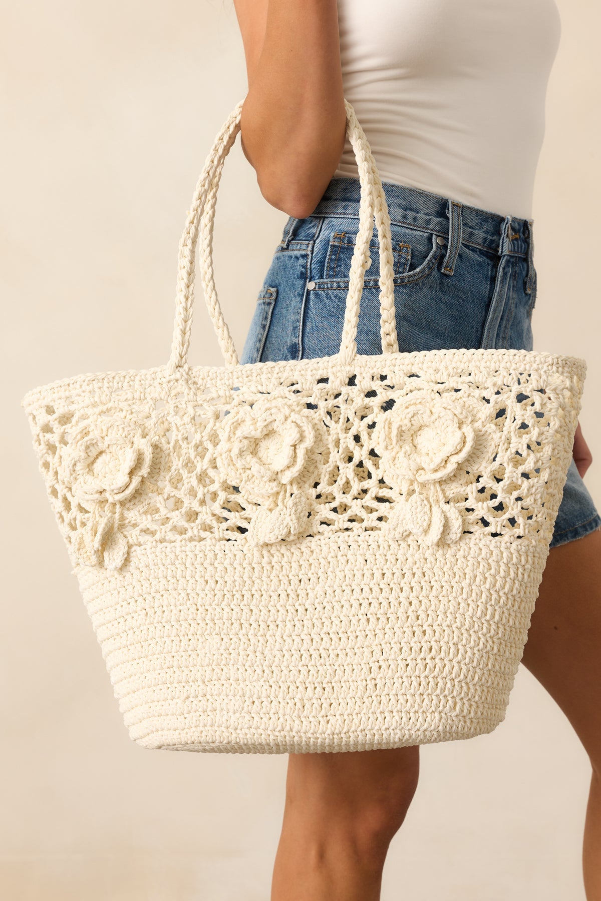 A full-length image of the ivory woven tote bag showcasing the open-tote design and three 3D floral appliqués on the front.