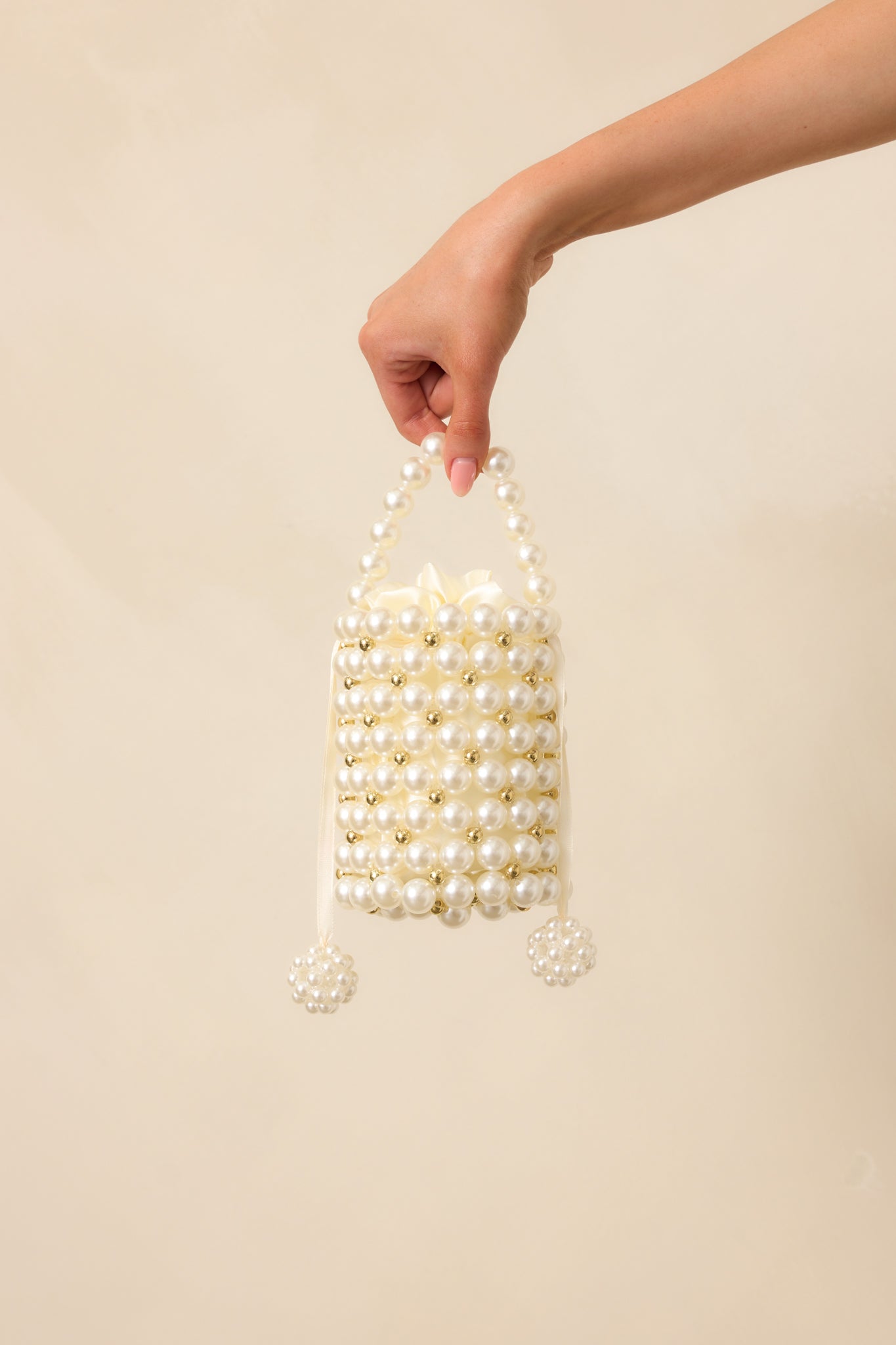 Complete frontal shot of the handbag highlighting the overall shape, optional pearl crossbody strap, and decorative pearl details.