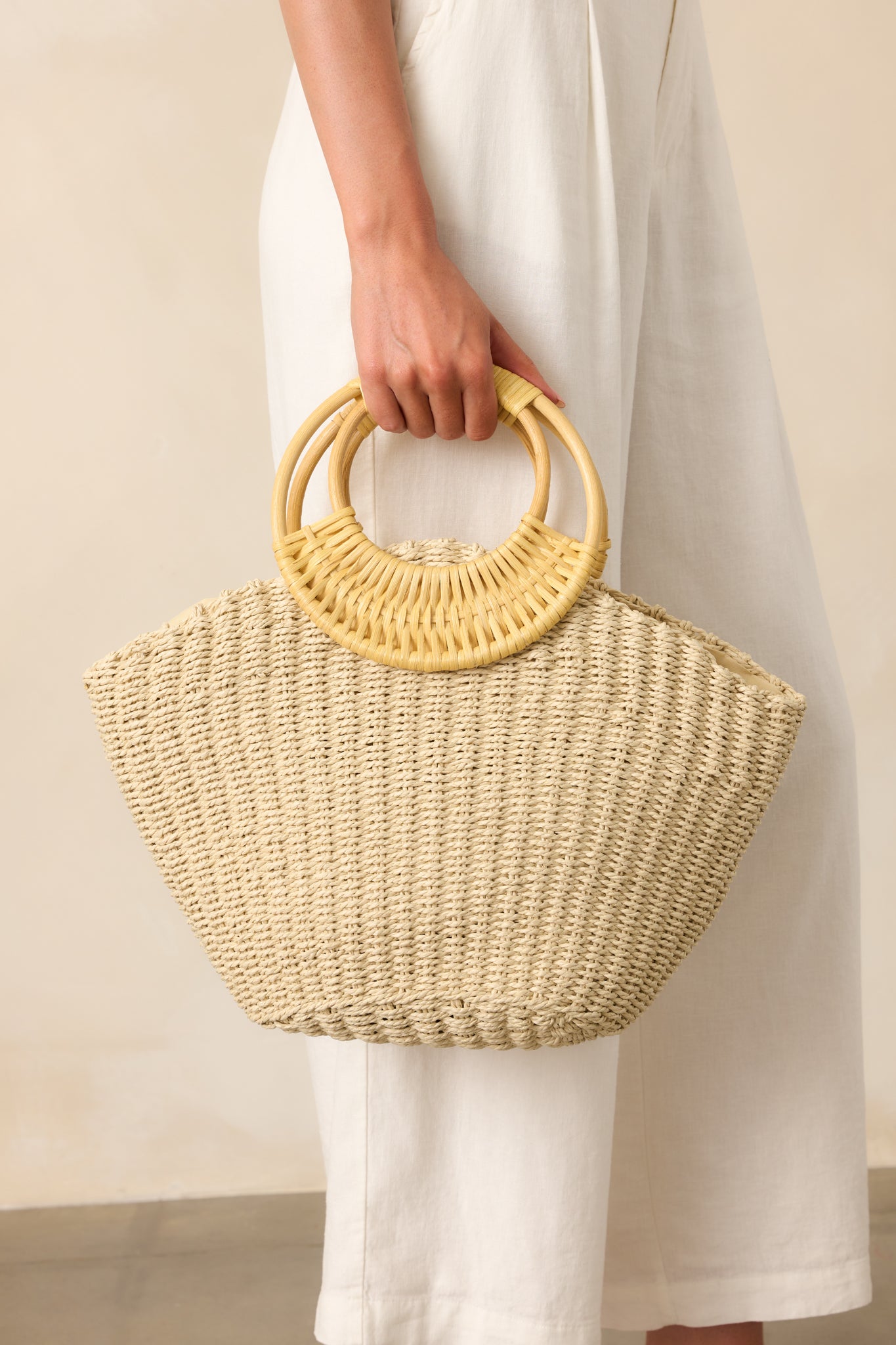 A cropped view highlighting the textured raffia woven fabric and the smooth finish of the natural bamboo handles.