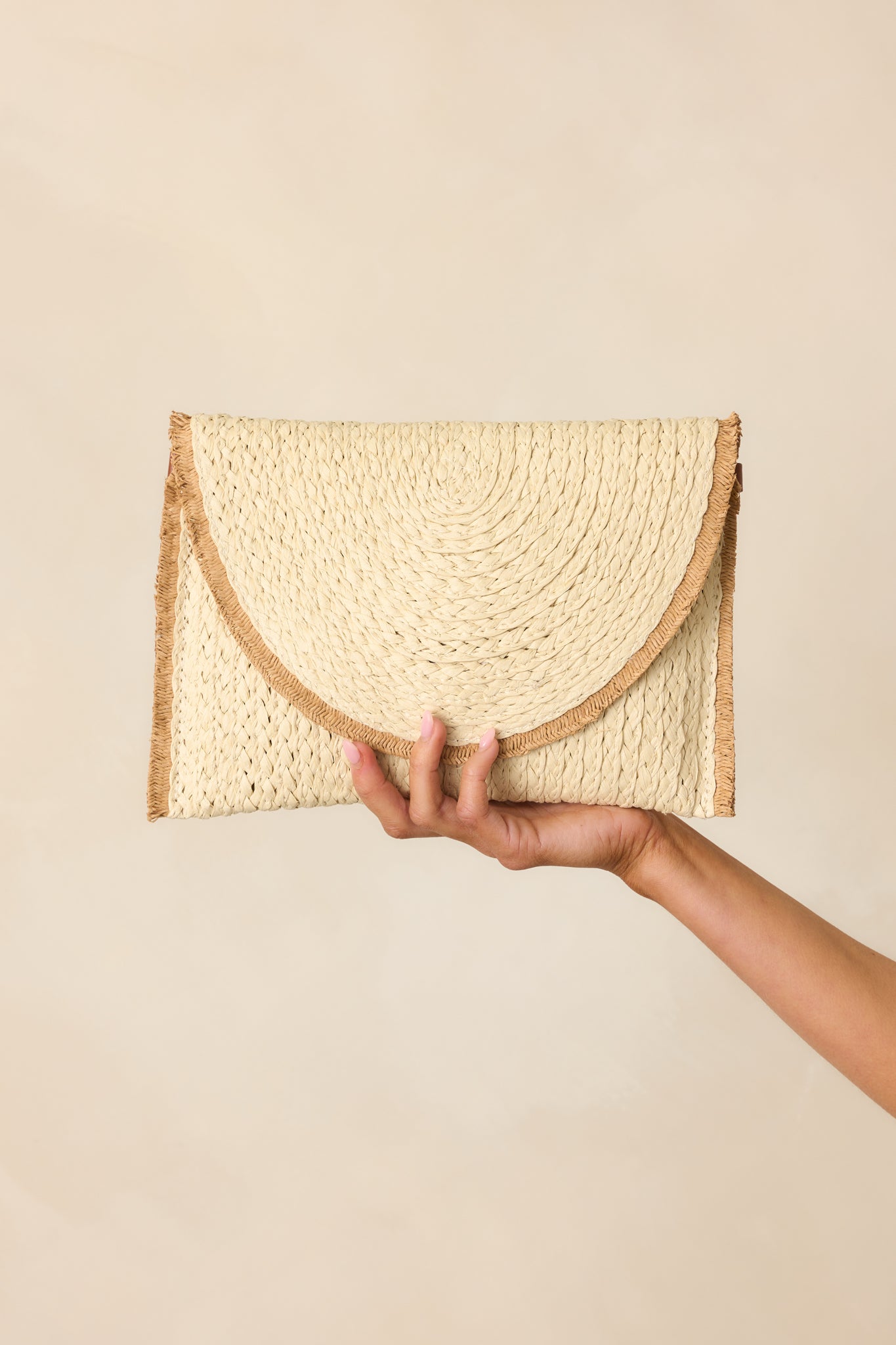 Full view of the ivory woven rattan handbag featuring frayed straw trim and a structured silhouette.
