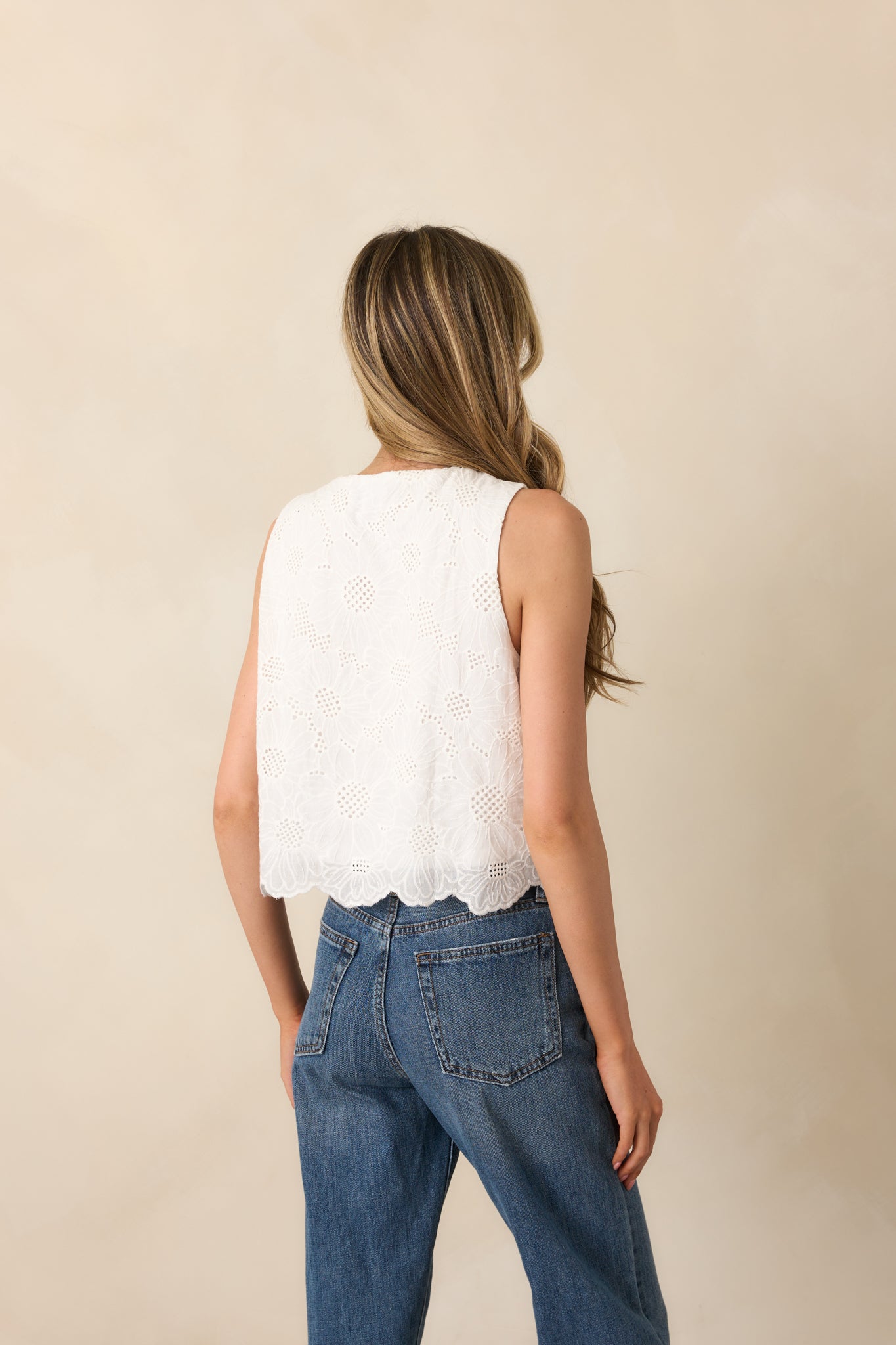 A view from behind of the white top, showing the sleeveless cut and continued eyelet embroidery.