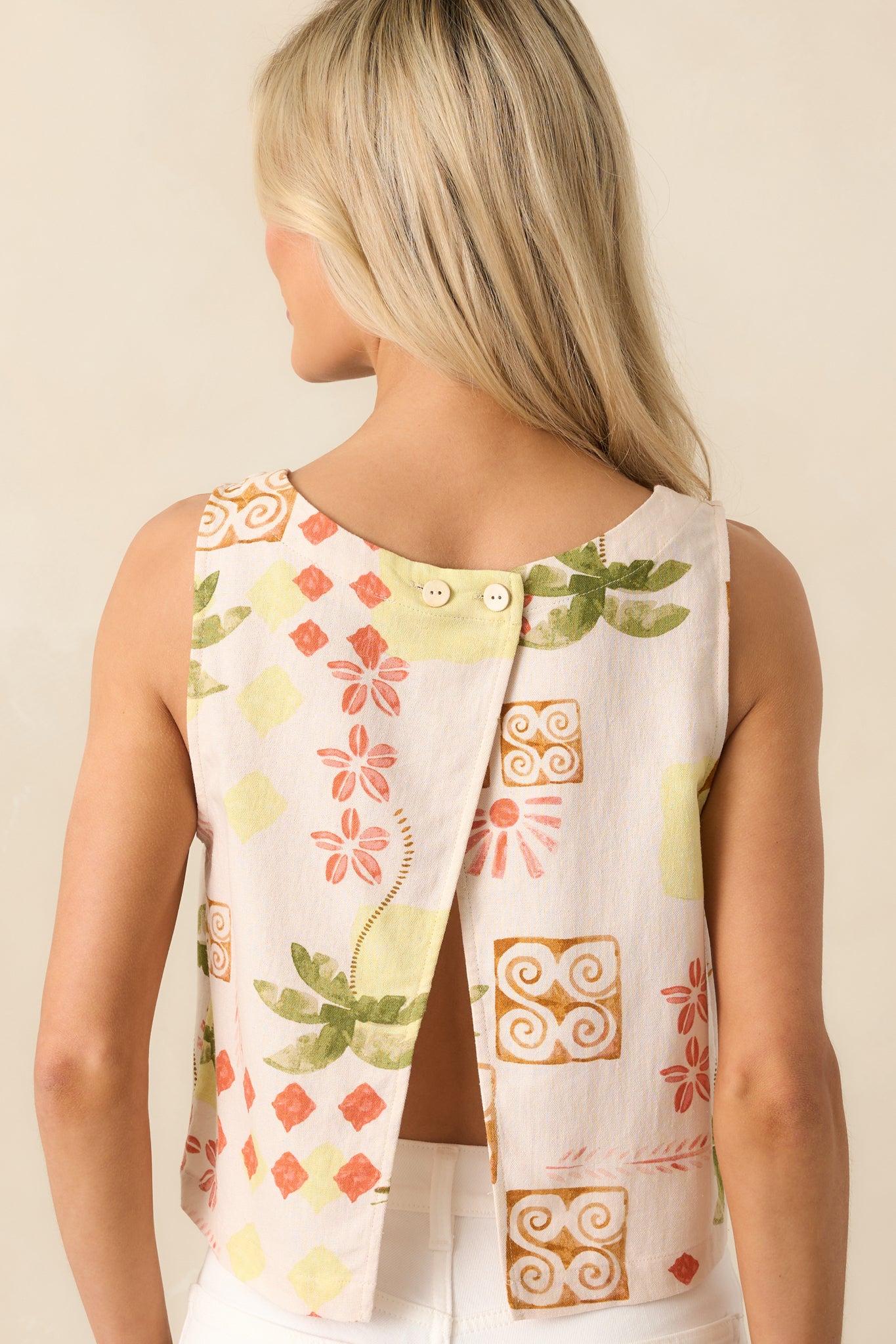 A view from behind of the top, showing the open back with a double button closure and continuation of the tropical print.