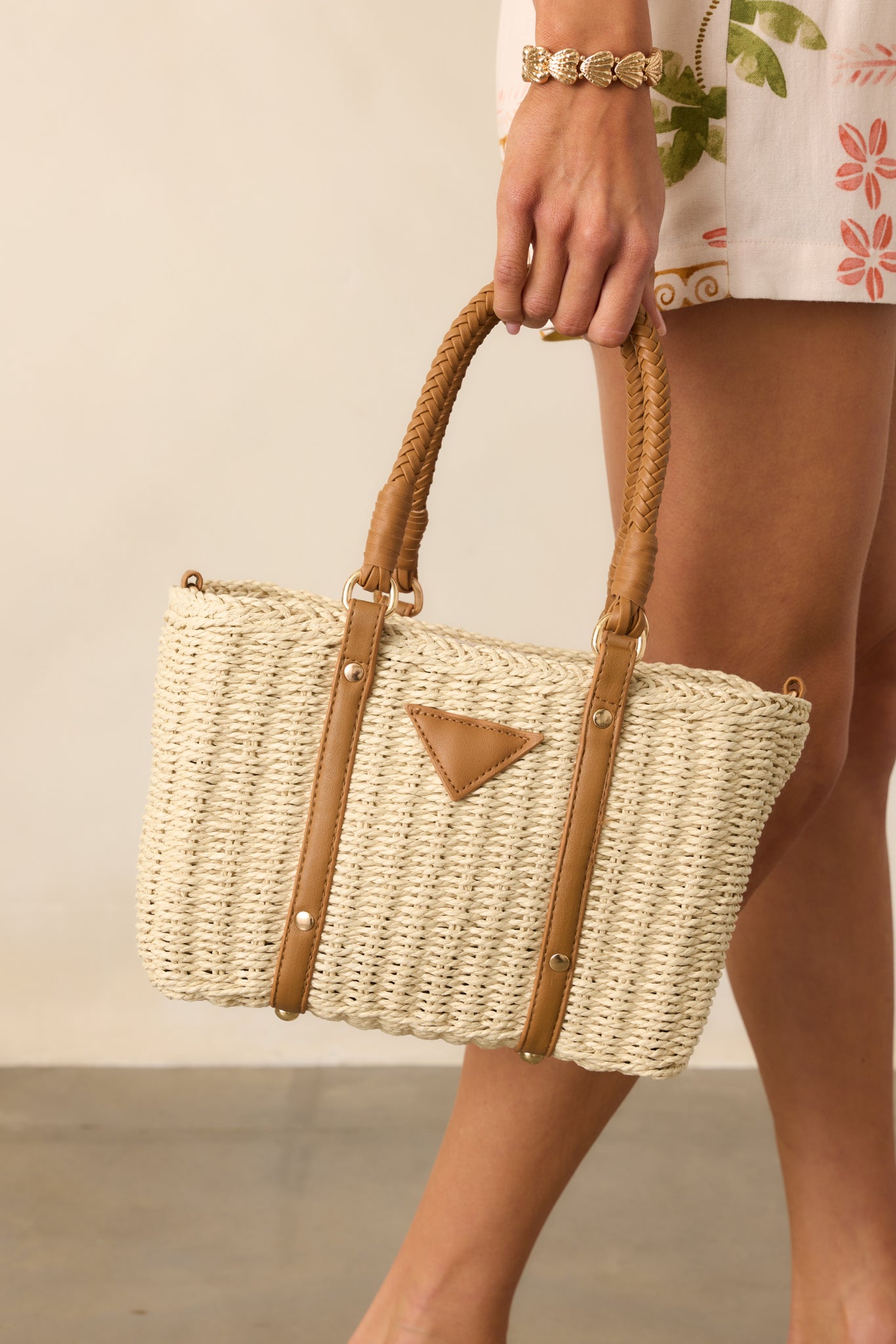 Cropped view focusing on the faux leather woven handles and zipper closure of the ivory handbag.