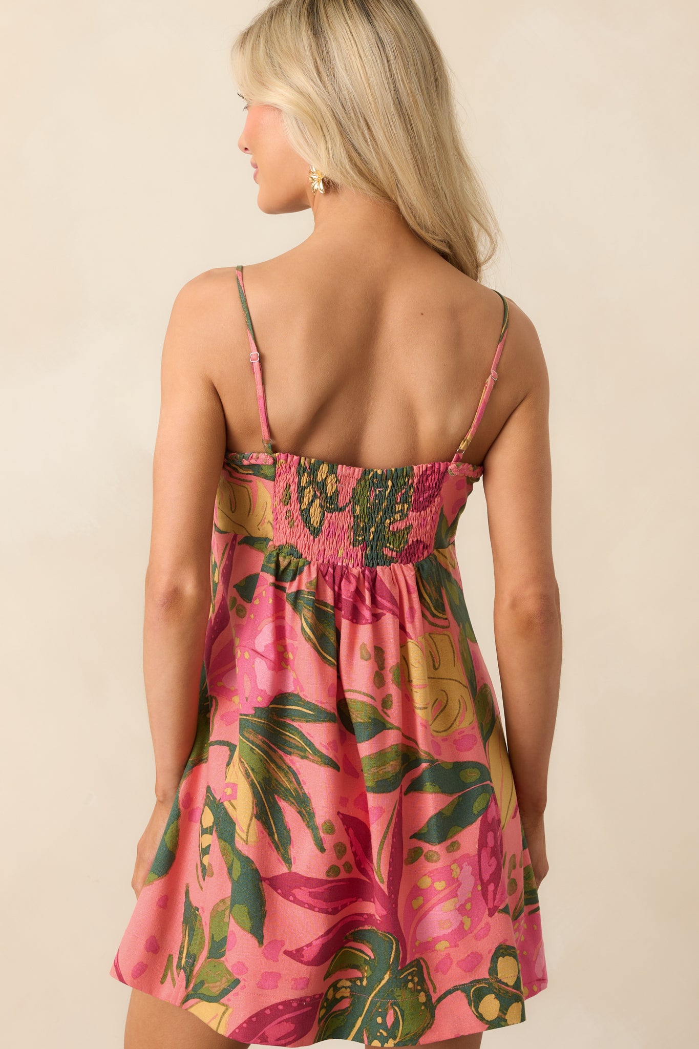 A view from behind of the mini dress, focusing on the smocked back panel and continuation of the tropical pattern.