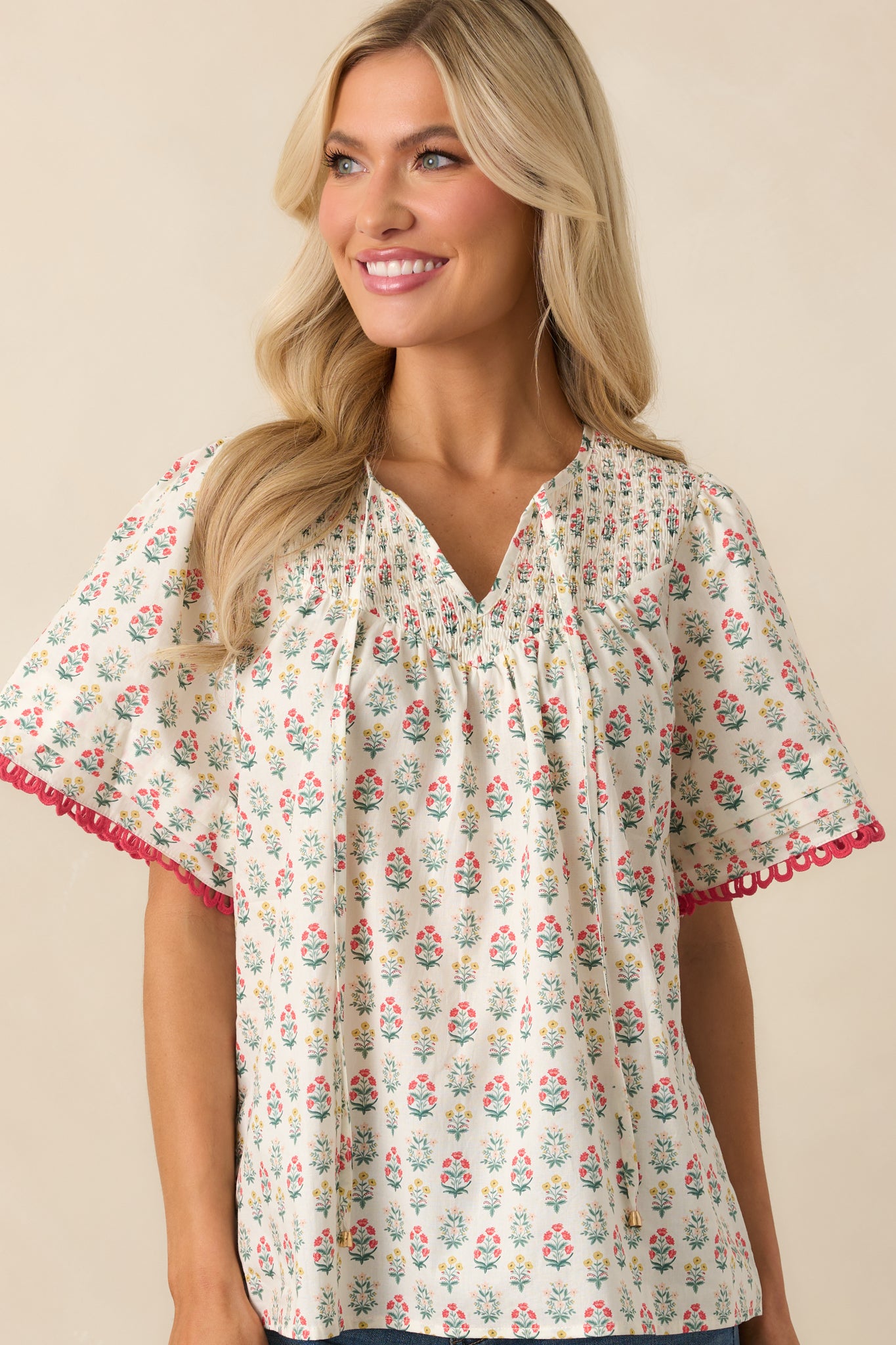 A cropped view focusing on the smocked yoke and optional self-tie front keyhole closure of the red multicolor floral top.