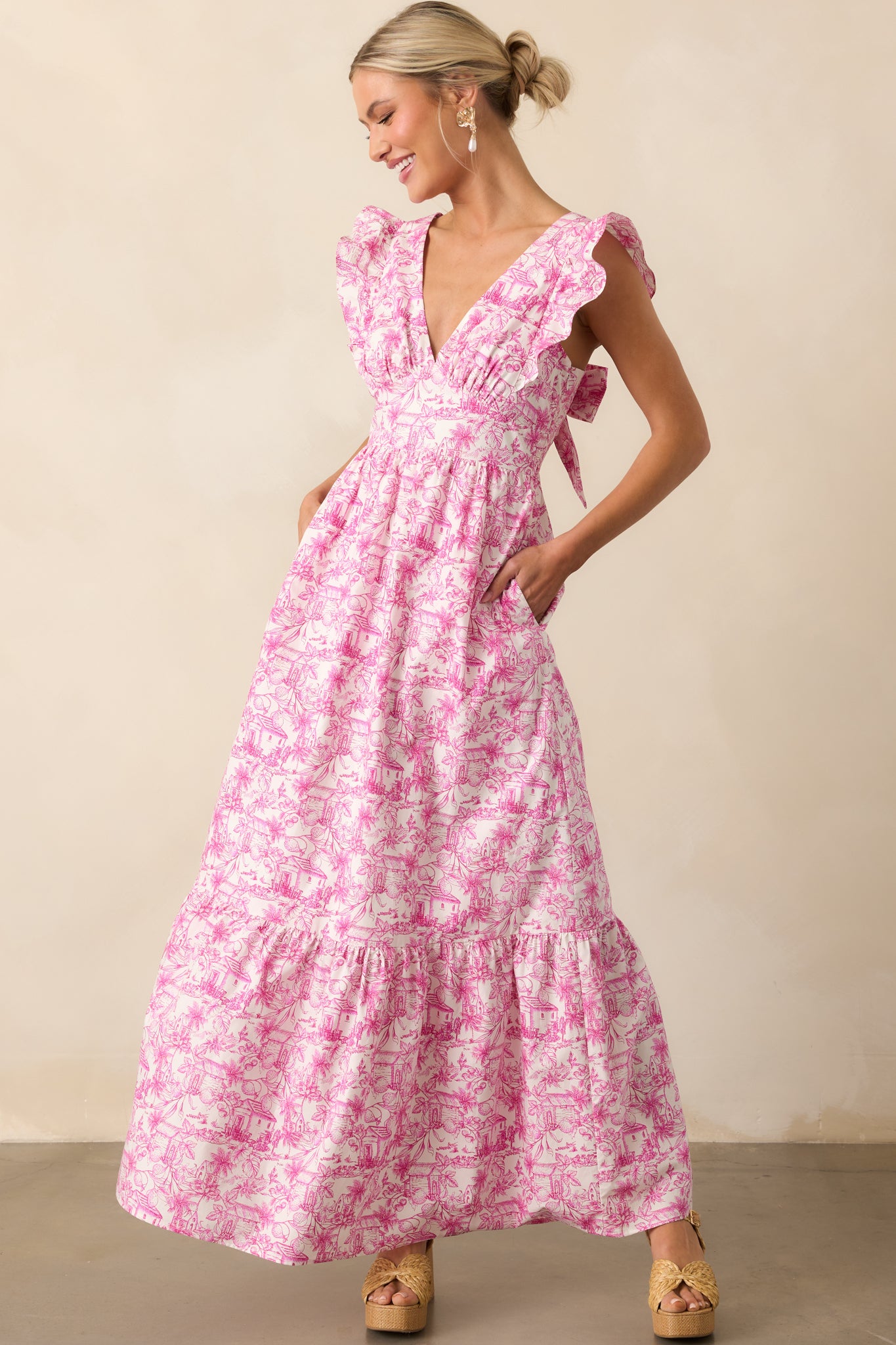 Pink tropical toile print maxi dress with a deep v-neckline and flutter sleeves shown from the front.
