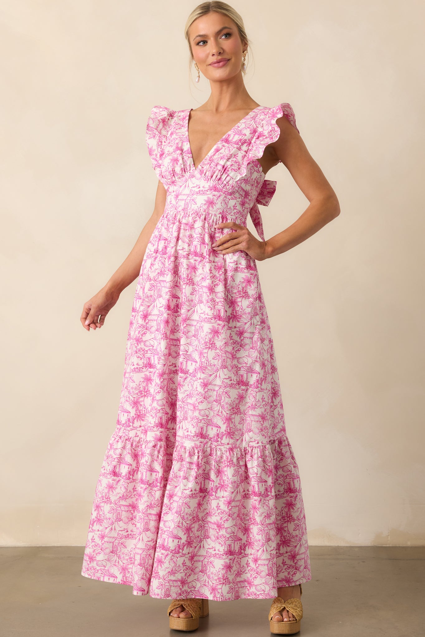Maxi dress with pink toile design, deep v-neck, and flutter sleeve details shown from the front.