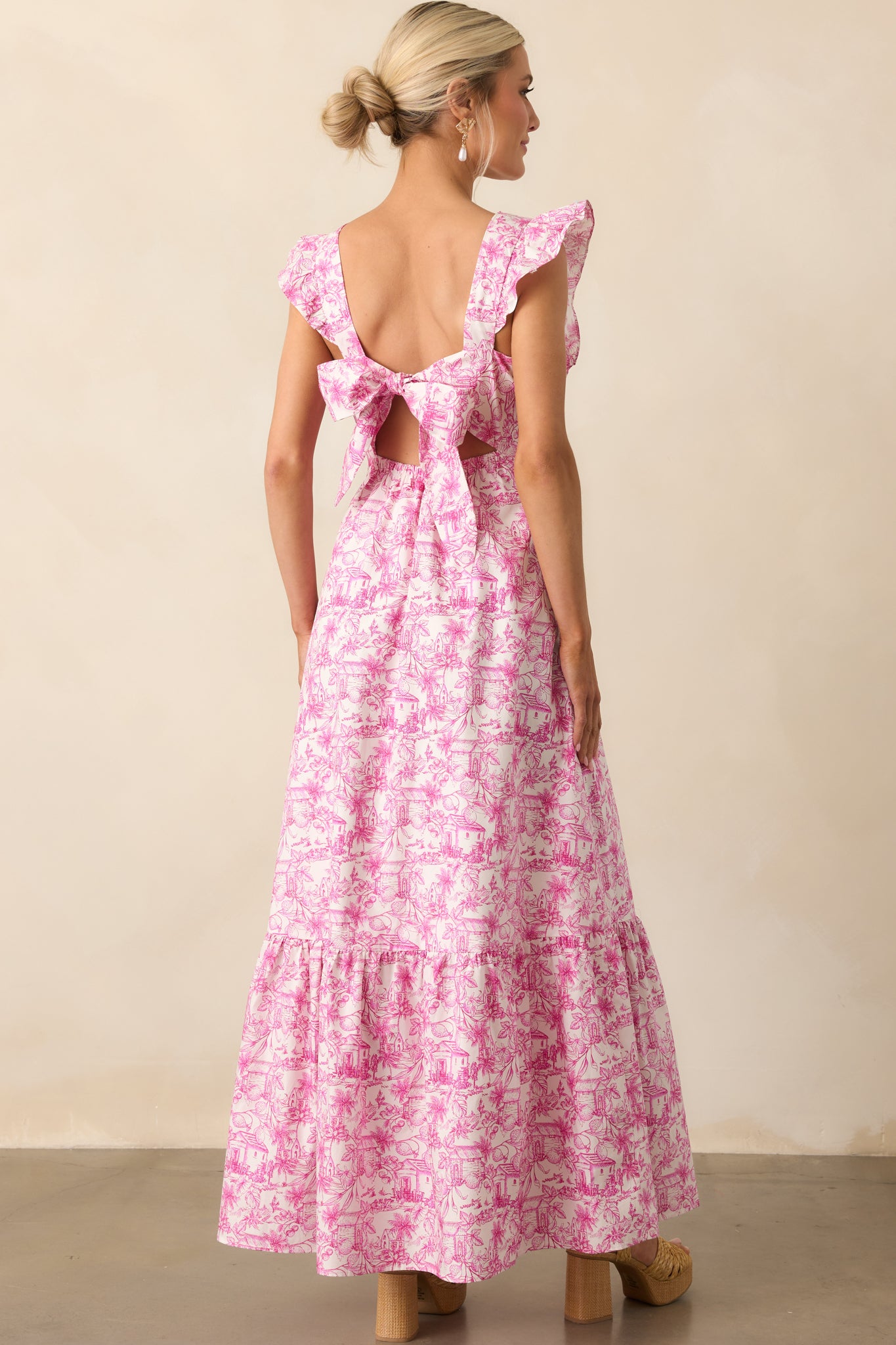 A view from behind of the pink toile print dress showing the open self-tie bow and elastic back waist insert.