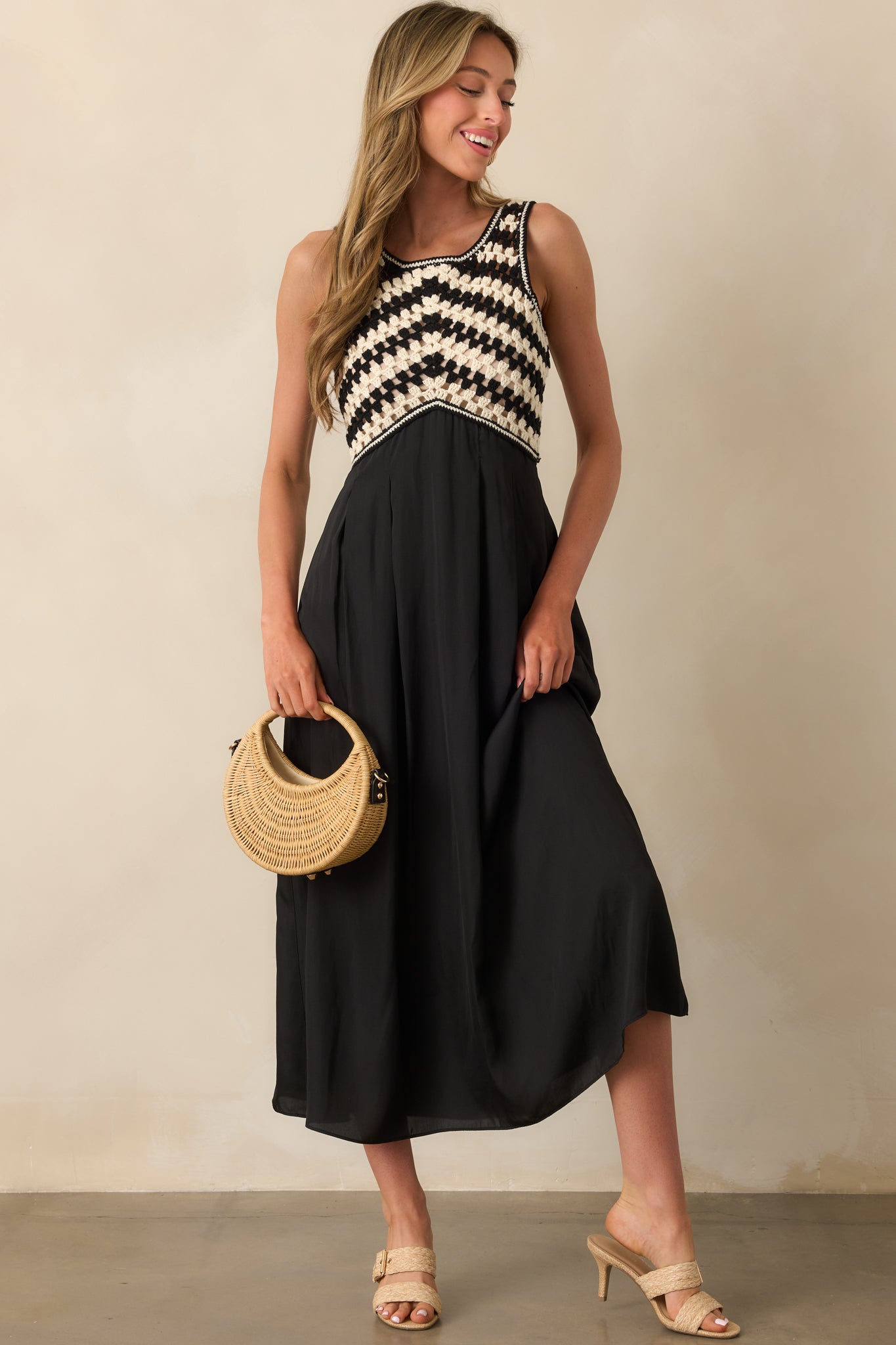 Full body image of black and white crochet top dress with high waist seam and pleated solid skirt.