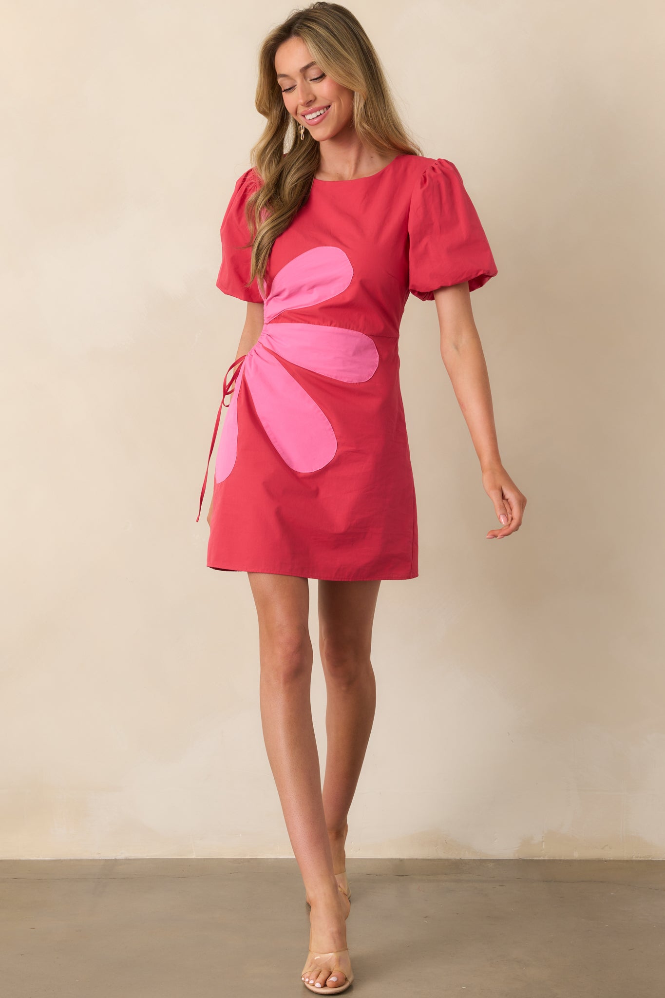 Full-length image of a red mini dress featuring adjustable side cut-outs and elastic sleeve cuffs.