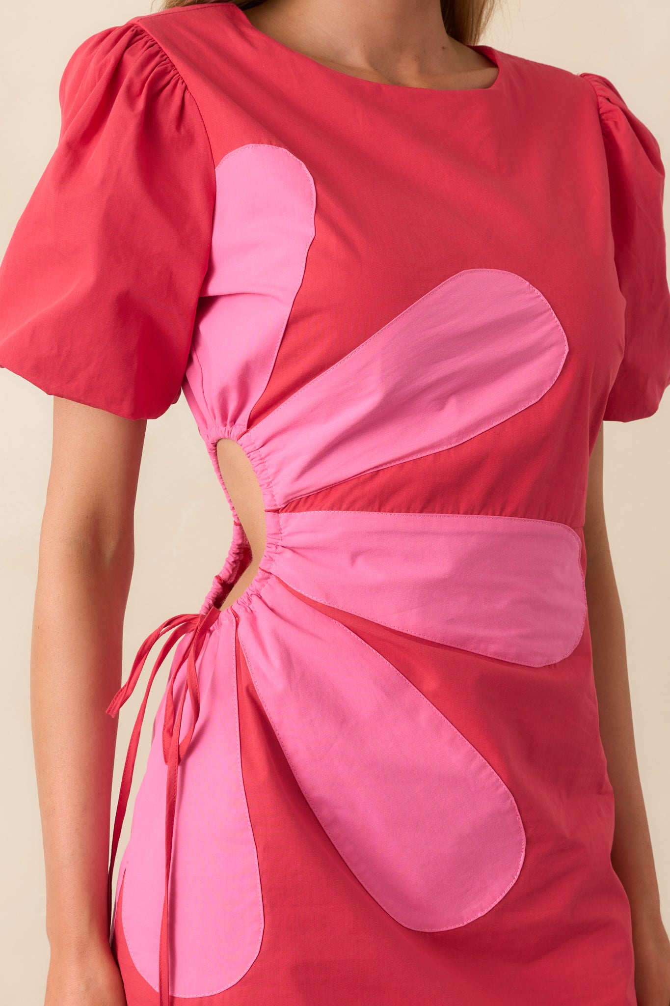 Close-up of the pink flower design on the red fabric, showing color contrast and stitching details.