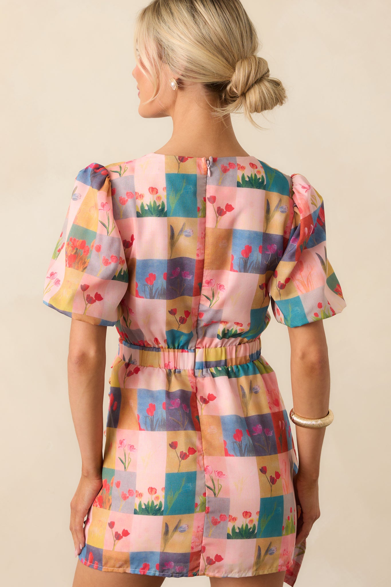 A view from behind of the blush pink mini dress, displaying the back elastic waist insert and hidden back zipper.