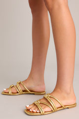 These gold sandals feature gold knotted straps, and a slip on design.