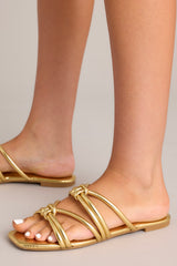 Close up view of these gold sandals that feature gold knotted straps, and a slip on design.