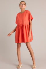 Angled front view of this dress that features a round neckline, a keyhole cutout at the back of the neck with a button closure, short sleeves, ruffle detailing along the waistline, and functional pockets at the hips.
