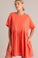 Full front view of this dress that features a round neckline, a keyhole cutout at the back of the neck with a button closure, short sleeves, ruffle detailing along the waistline, and functional pockets at the hips.